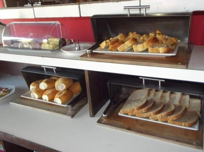 Buffet com diversos pães e doces em recipientes.