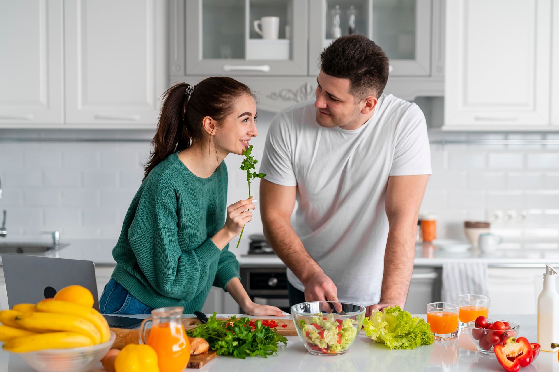 Un hombre y una mujer están preparando una ensalada en una cocina.