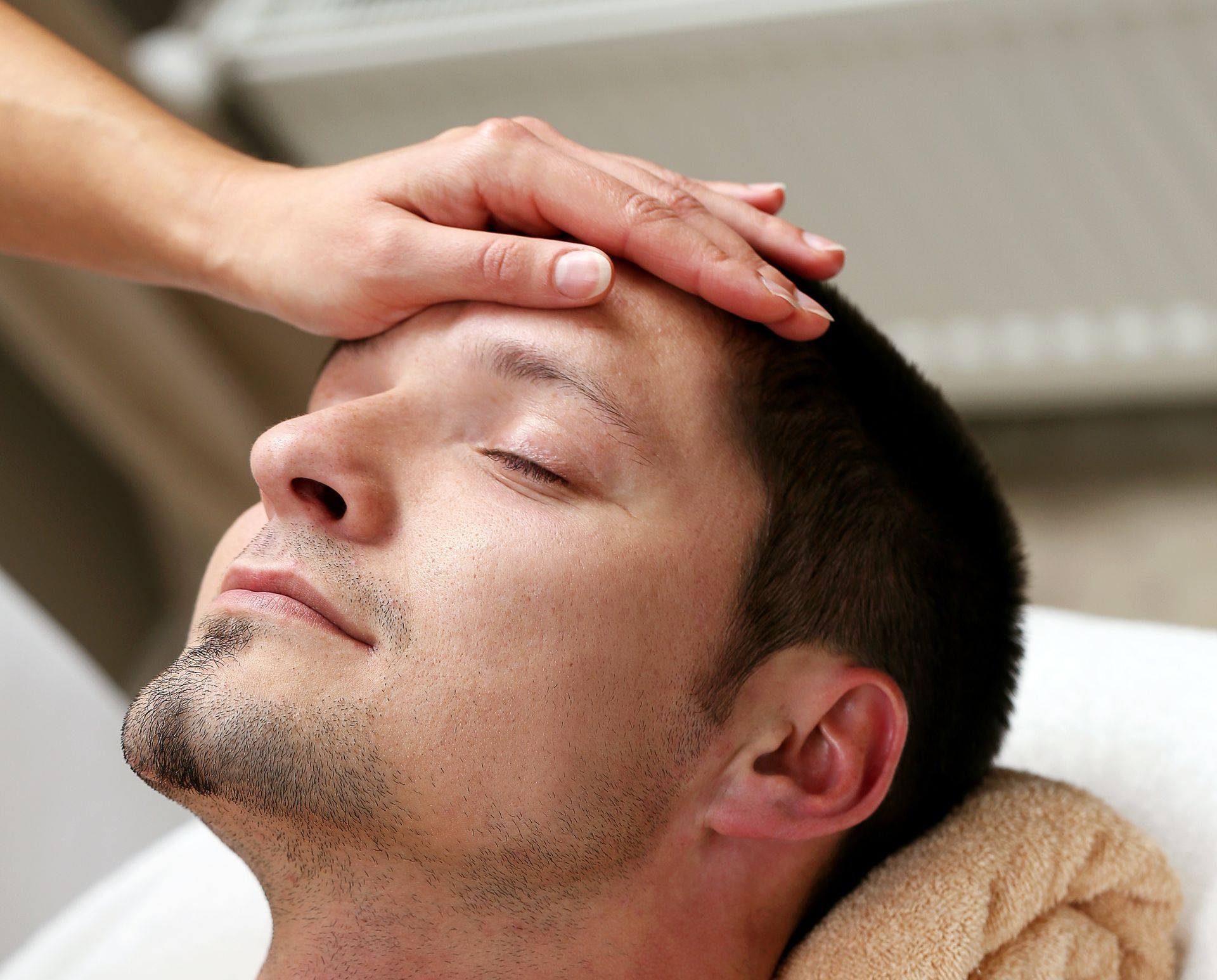 Un hombre recibe un masaje en la cabeza con los ojos cerrados.