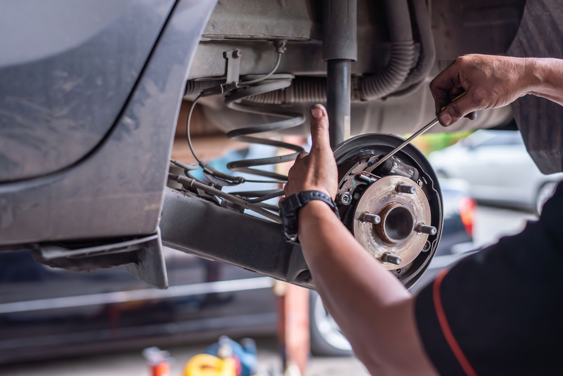 Mechanic repairing car brakes in a brake shop with tools and equipment inside a garage.