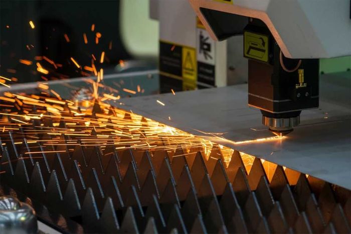 machine is cutting a piece of metal with sparks coming out of it.