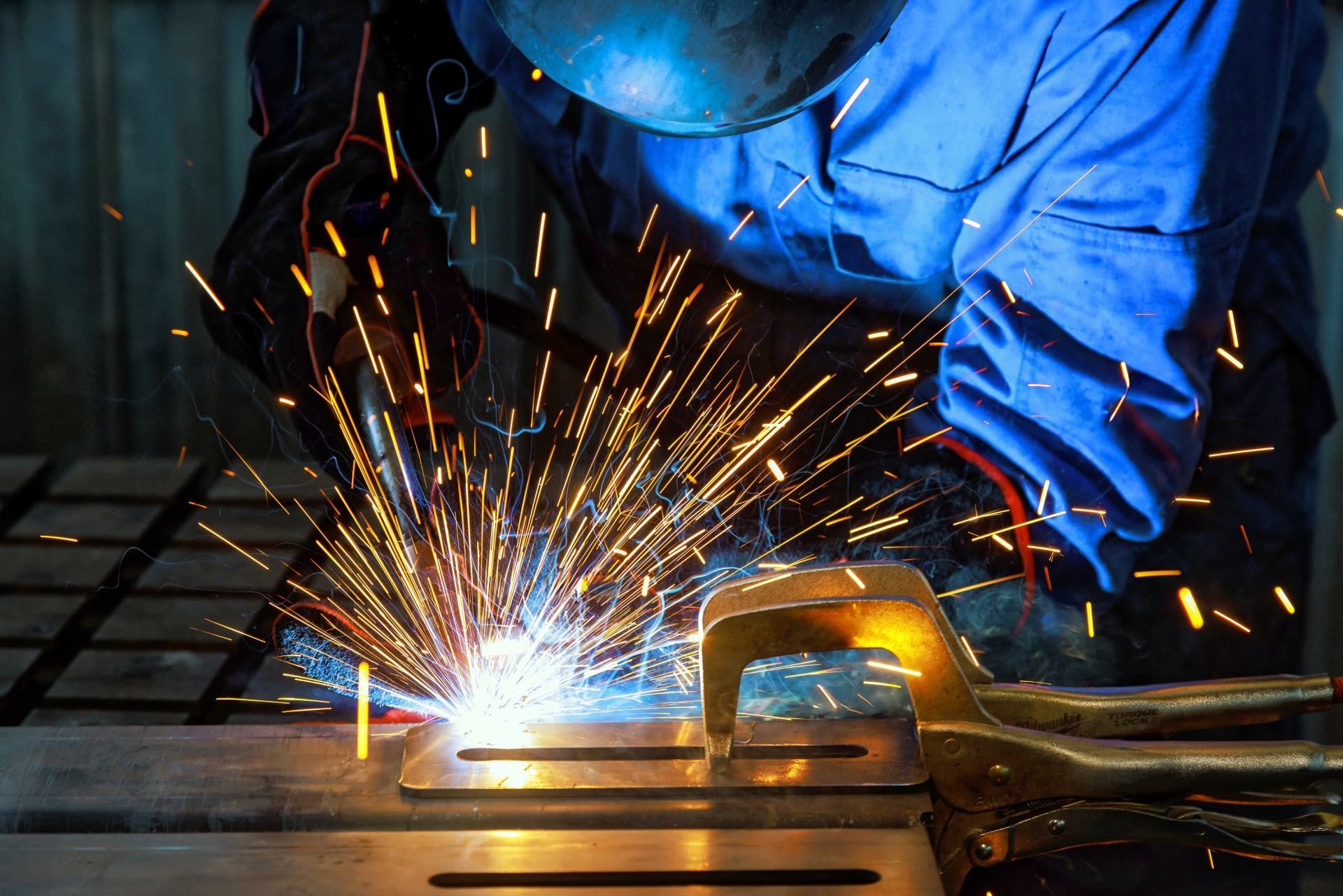 A man is welding a piece of metal with sparks coming out of it.