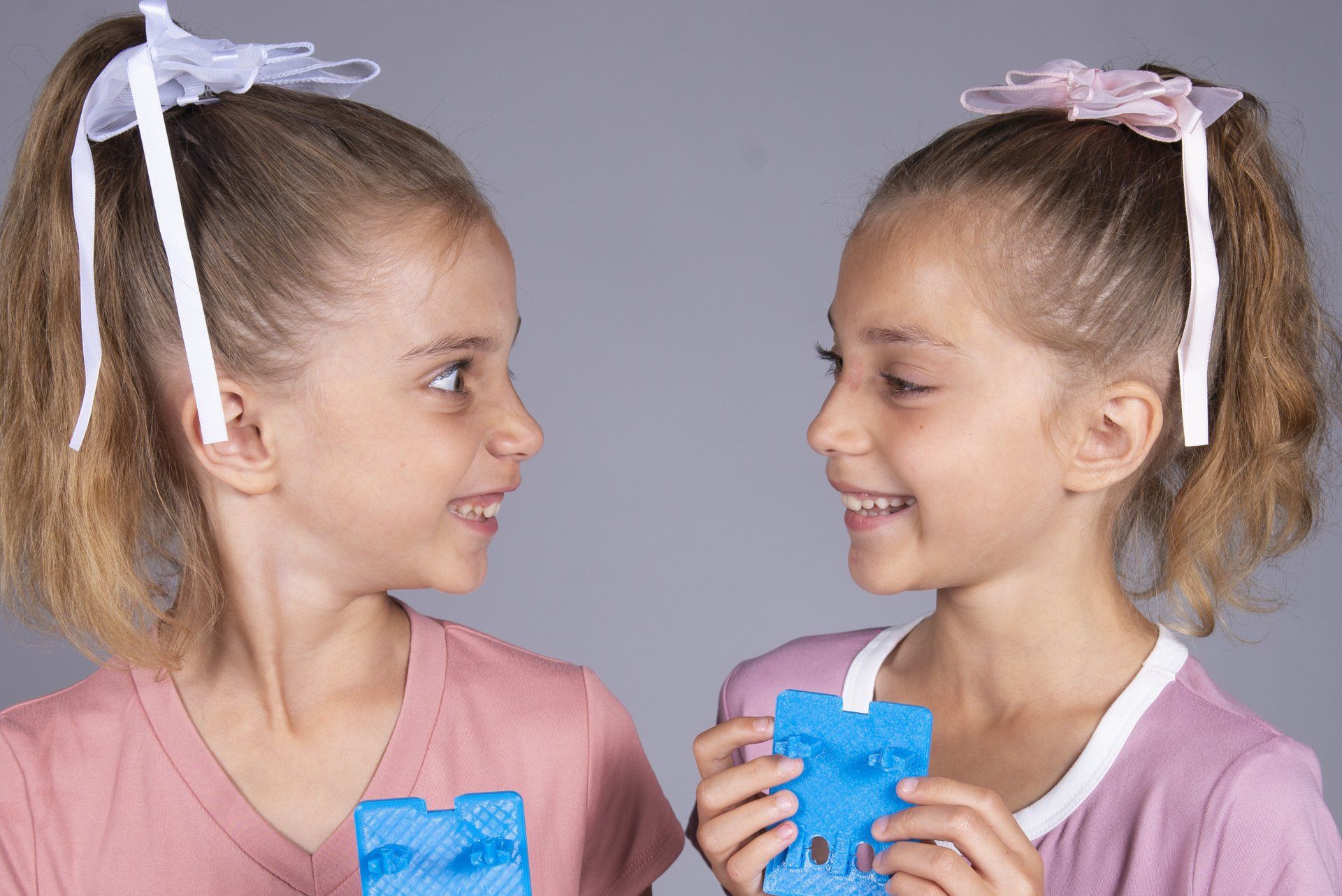 Two little girls are standing next to each other holding a piece of paper.