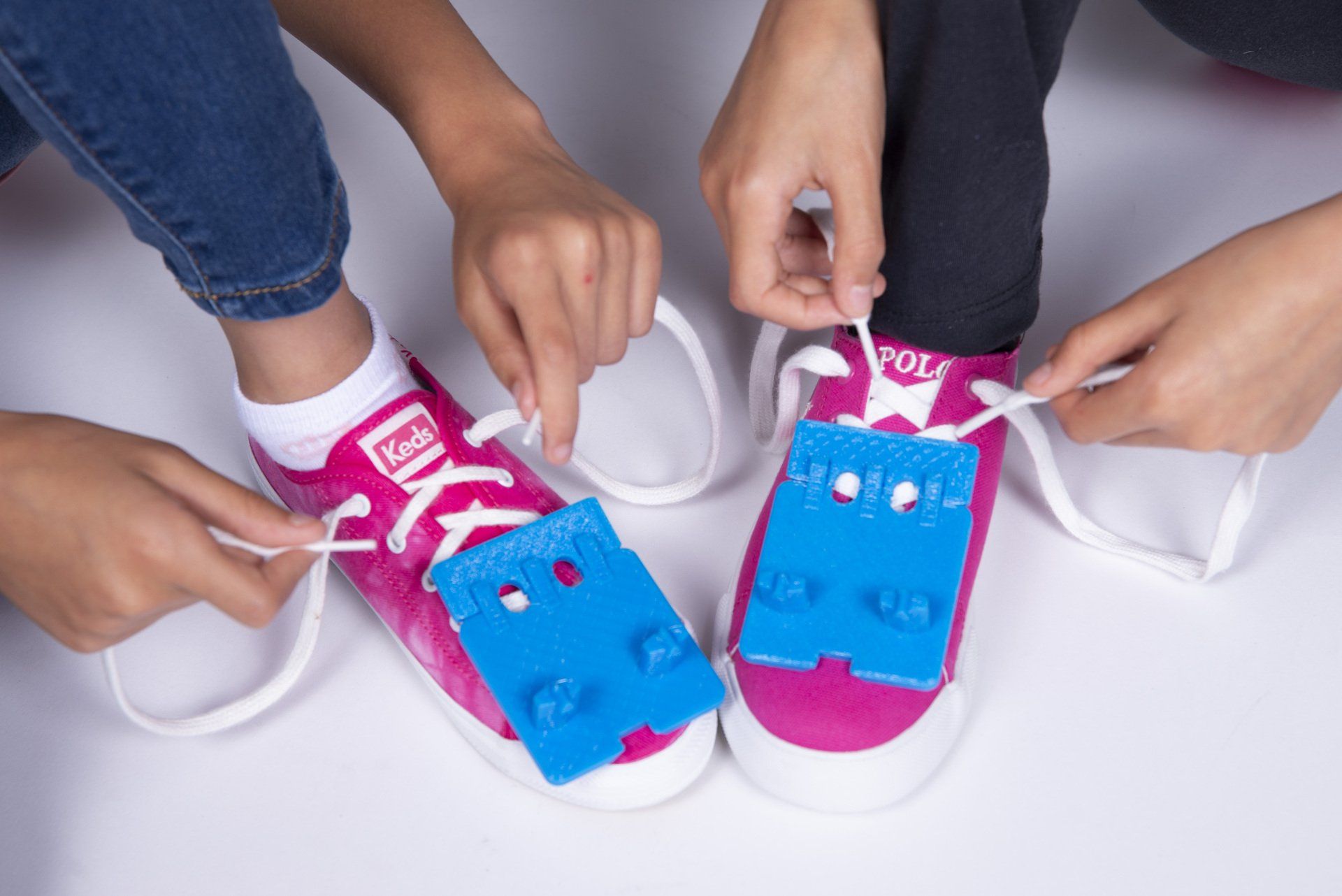 Two children are tying their shoes with lego blocks.