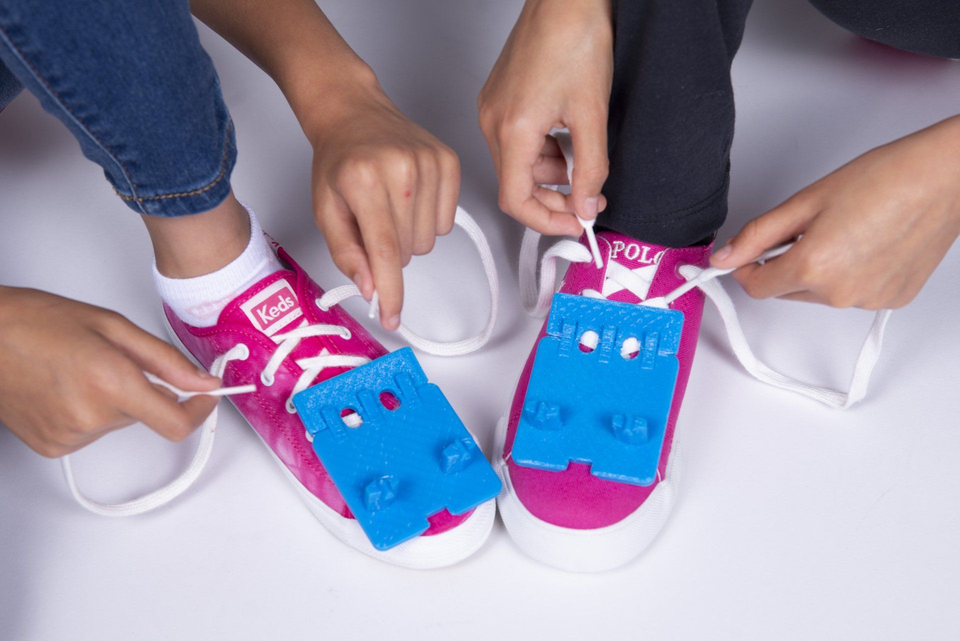 Two children are tying their shoes with lego blocks.