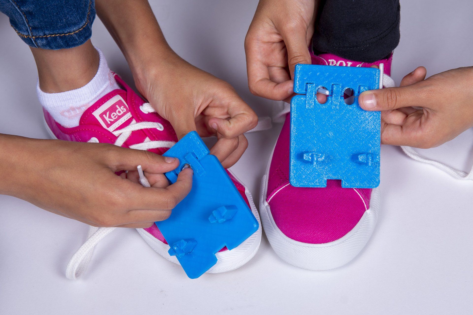 A person is tying a pair of pink keds shoes.
