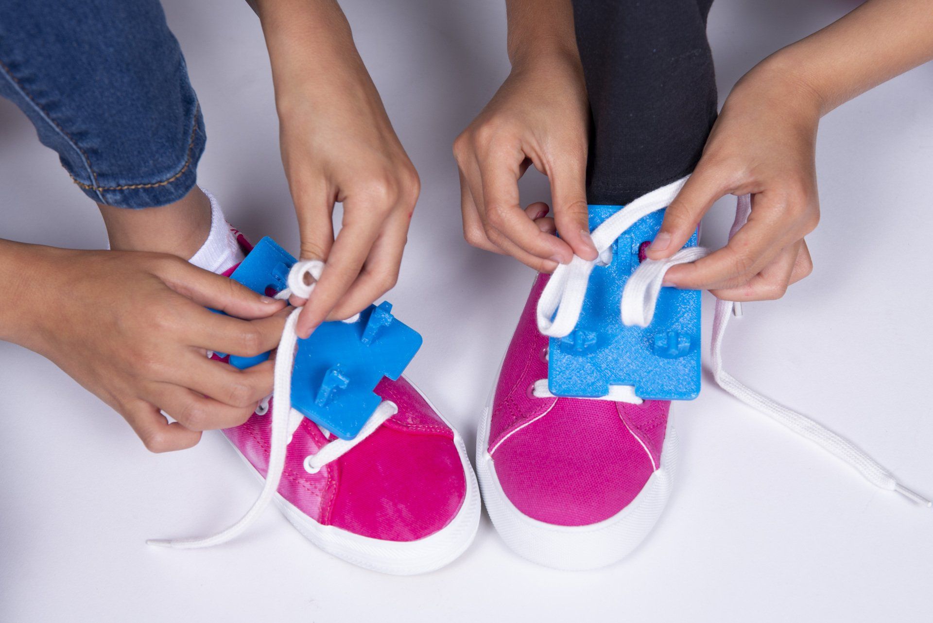 A person is tying a pair of pink and blue shoes