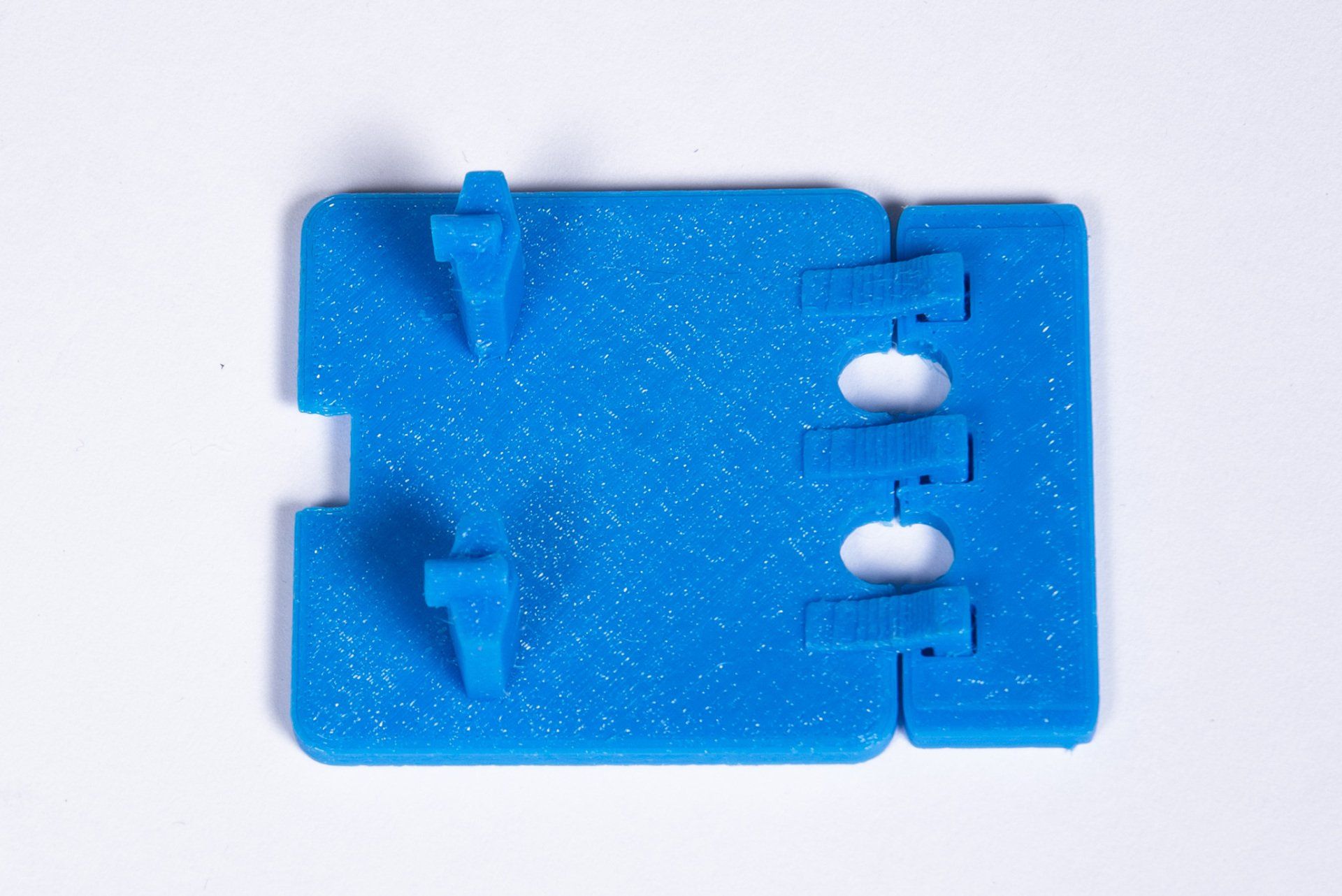 A blue plastic item with holes in it is sitting on a white surface.