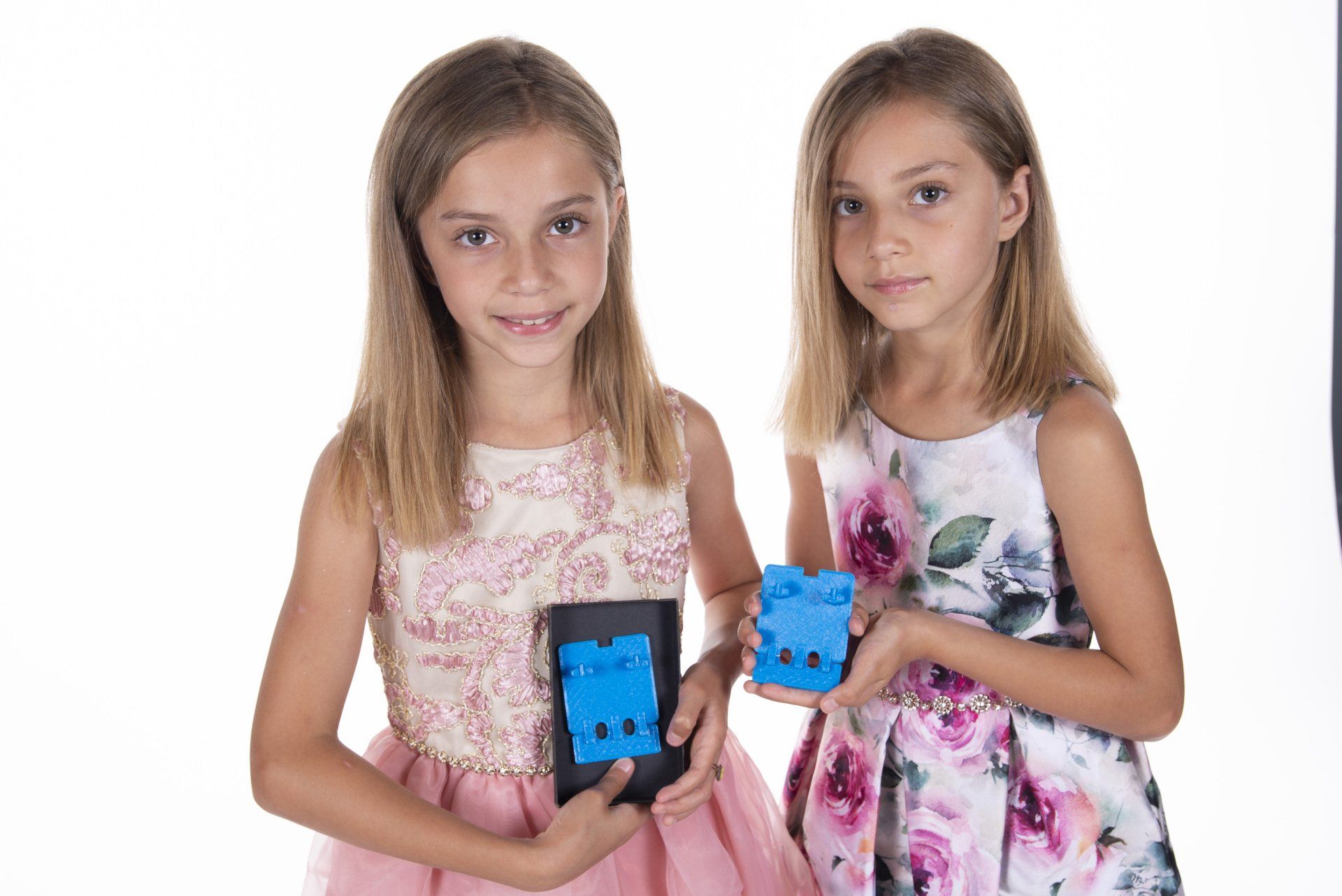 Two little girls are holding blue blocks in their hands.