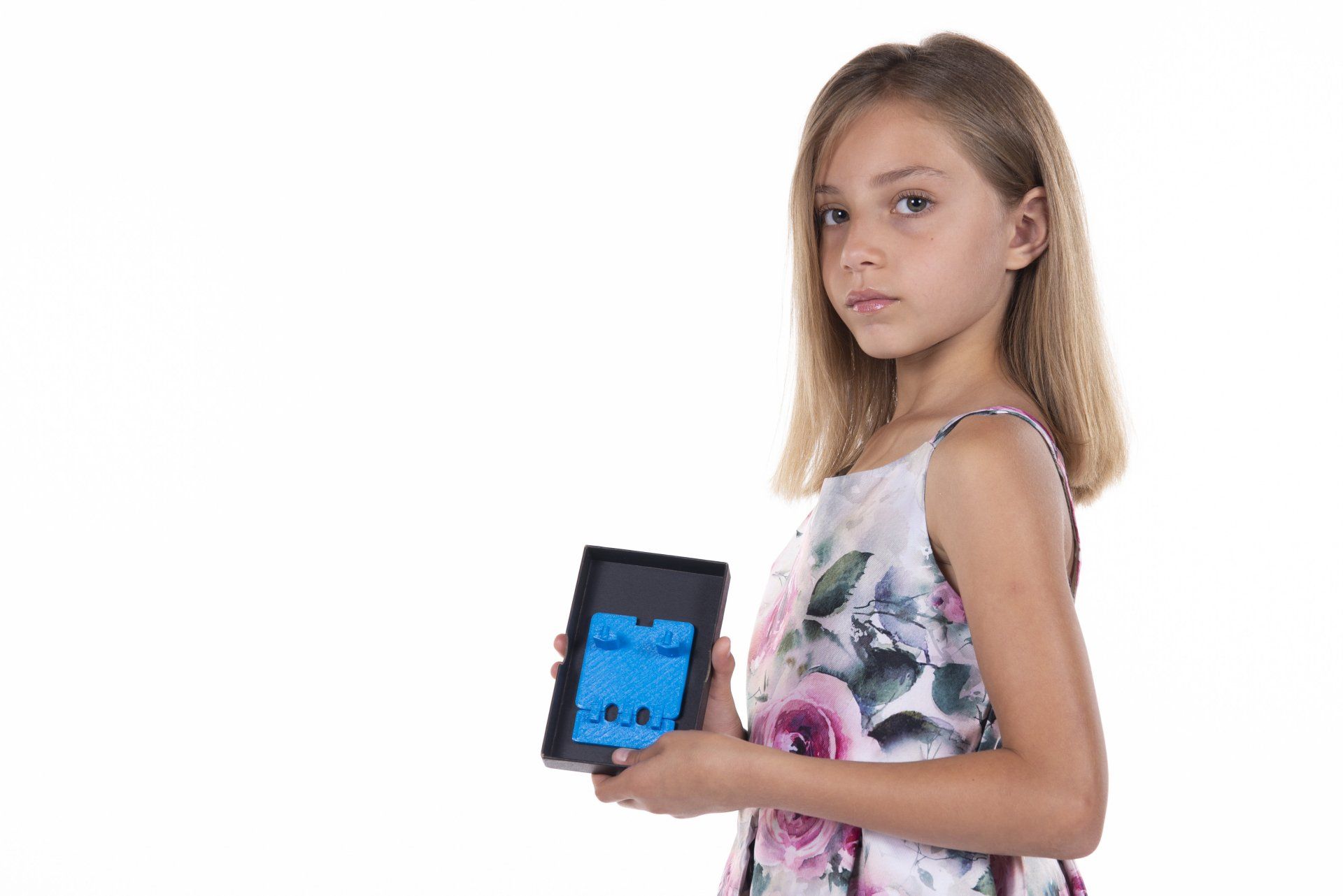 A young girl in a floral dress is holding a tablet computer.