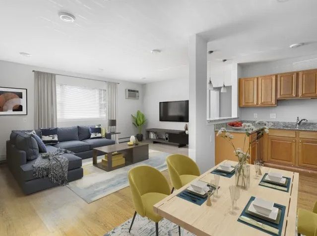 A picture took from the dining room area overlooking the living room with dining set, sofa, TV, and oversized window.