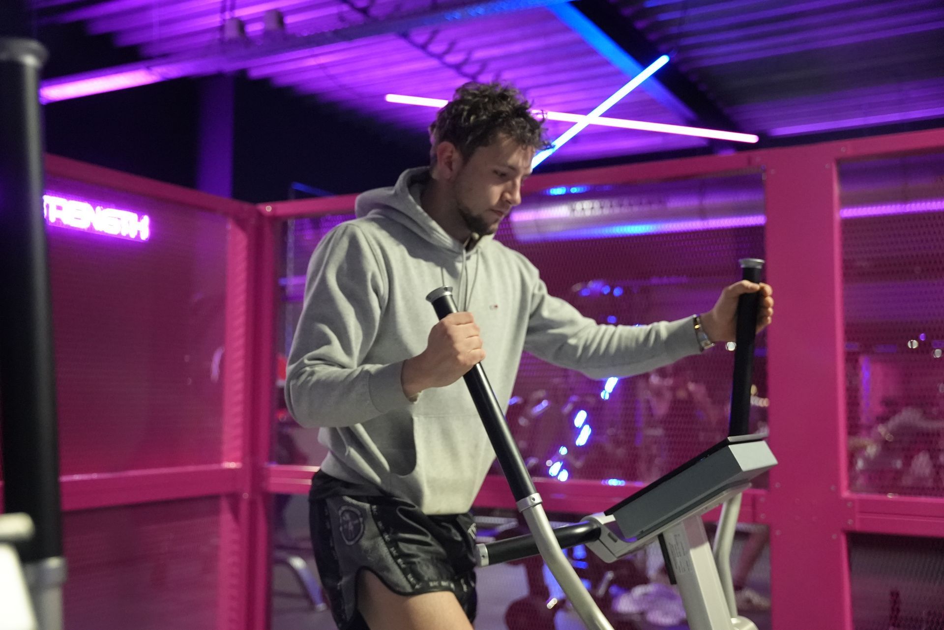 Een man rijdt op een crosstrainer in een sportschool.