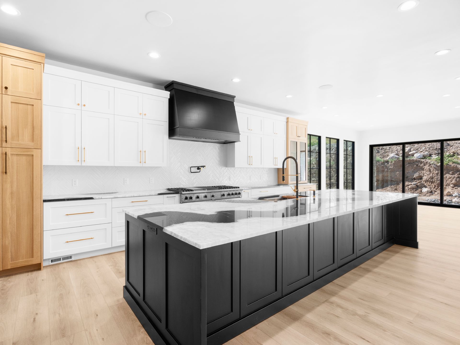 A kitchen with black cabinets and white counter tops and a large island in the middle.