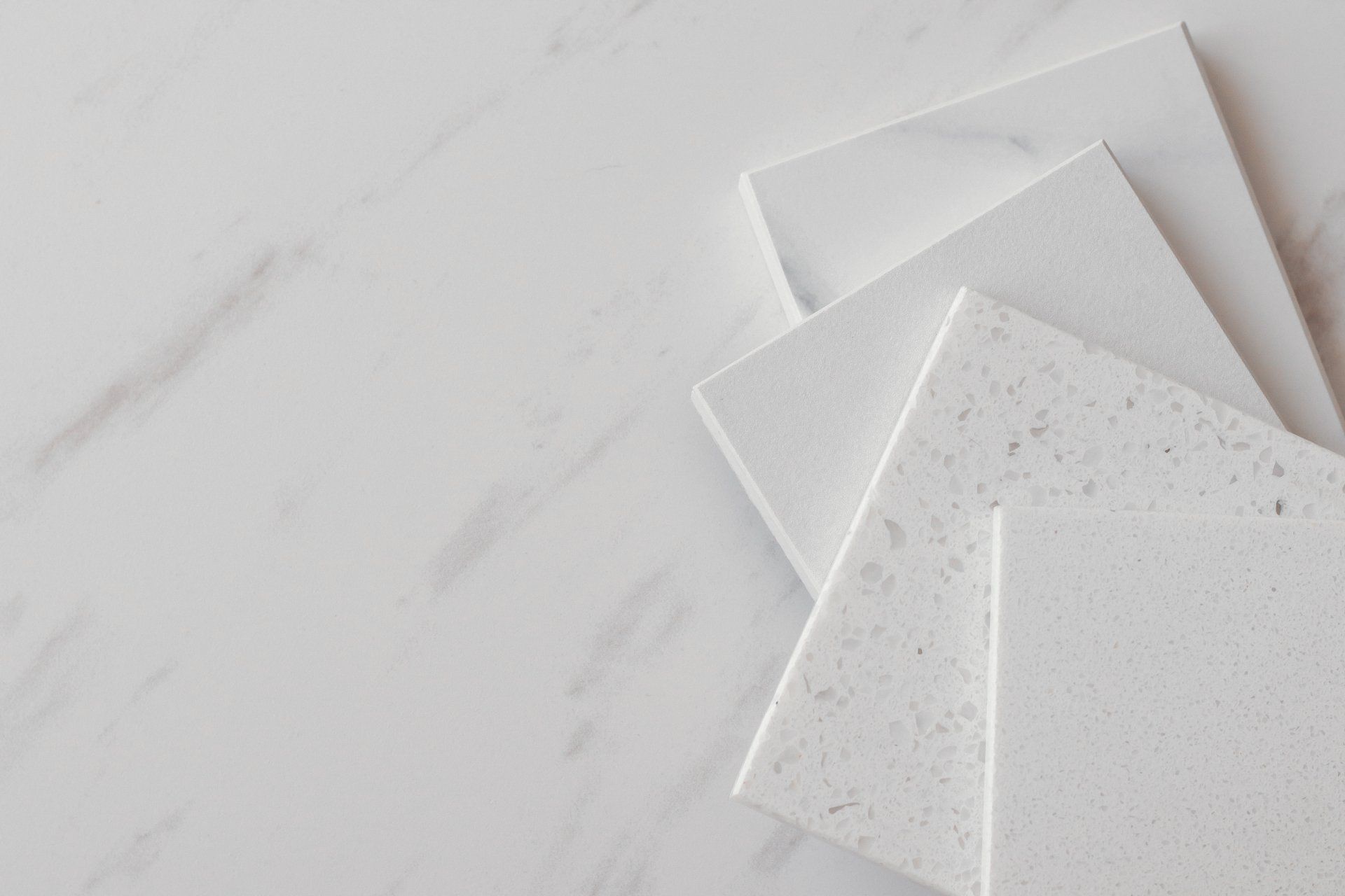 Trois tuiles blanches sont empilées les unes sur les autres sur une surface en marbre blanc.