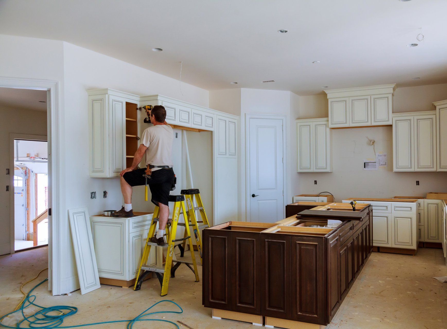 Un homme est debout sur une échelle dans une cuisine.