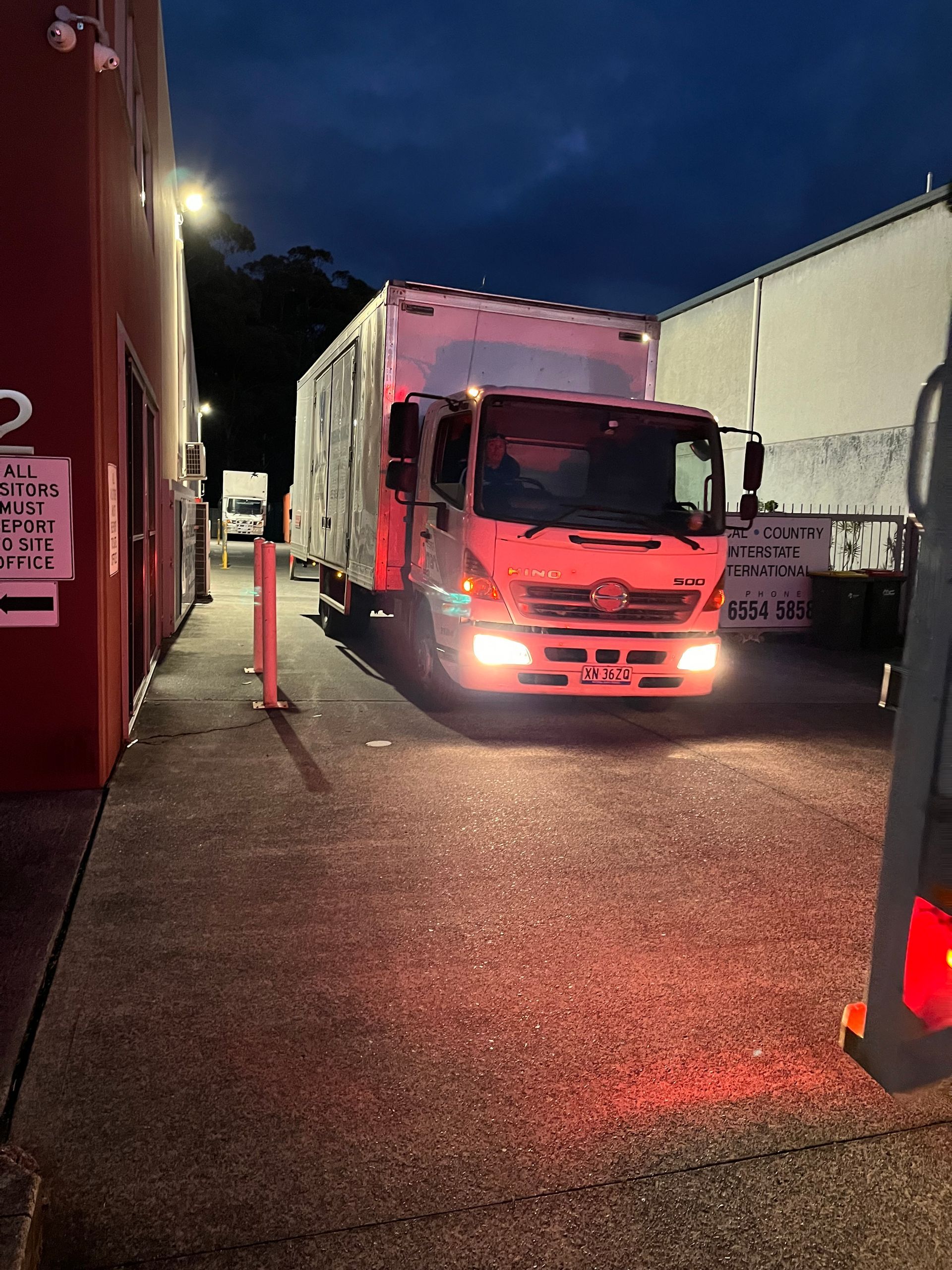 A Red Truck is Parked in a Parking Lot at Night — Forster Tuncurry Removals & Storage in Old Bar, NSW