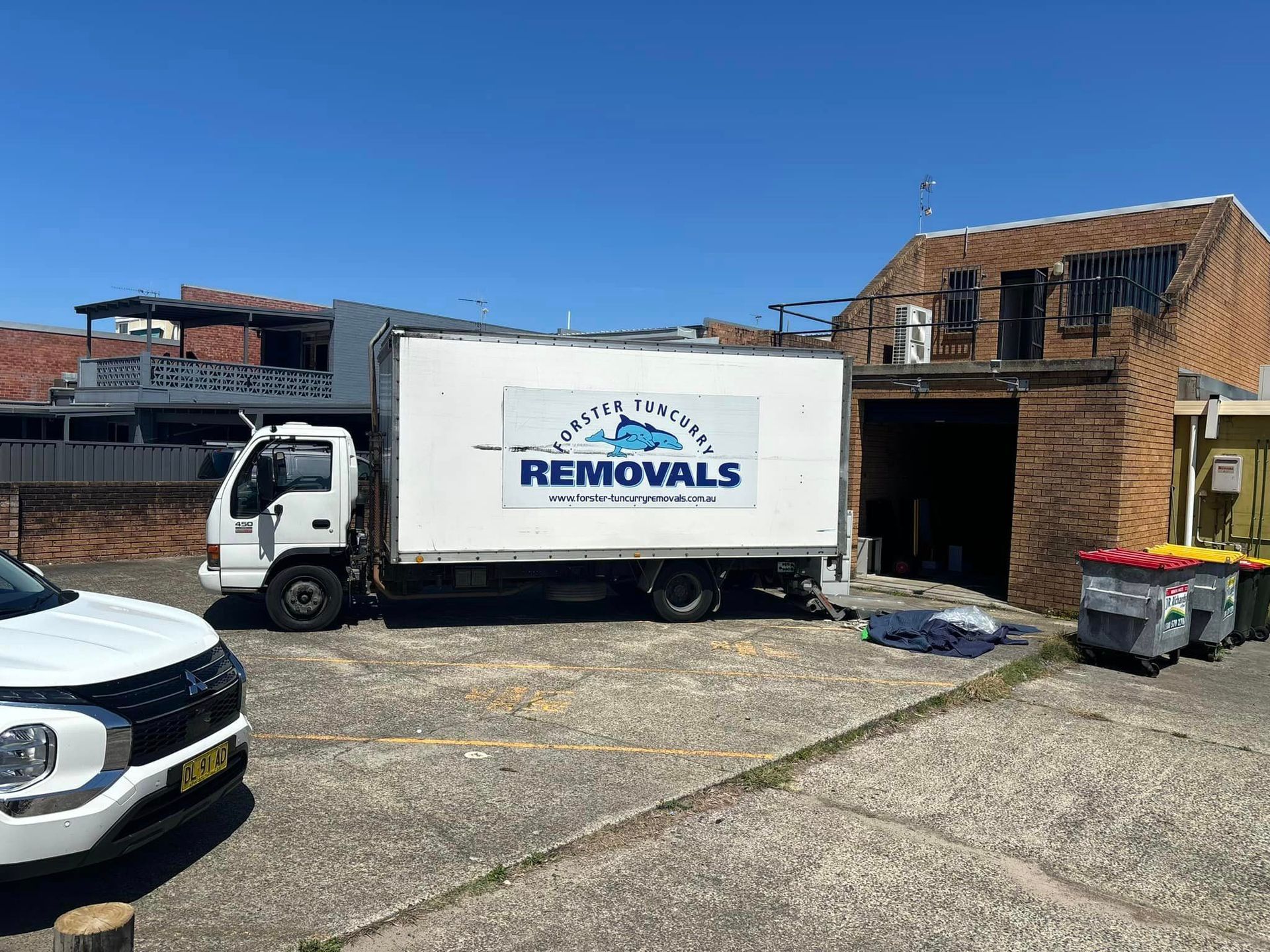 A Removals Truck is Parked in Front of a Building — Forster Tuncurry Removals & Storage in Tuncurry, NSW