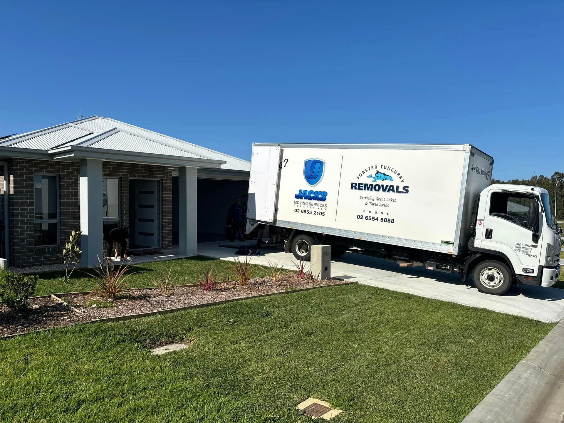 A Moving Truck is Parked in Front of a House — Forster Tuncurry Removals & Storage in Tuncurry, NSW