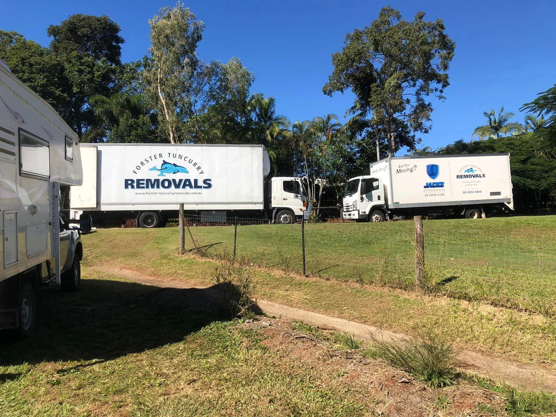 Two Removal Trucks Are Parked in a Grassy Field — Forster Tuncurry Removals & Storage in Tuncurry, NSW