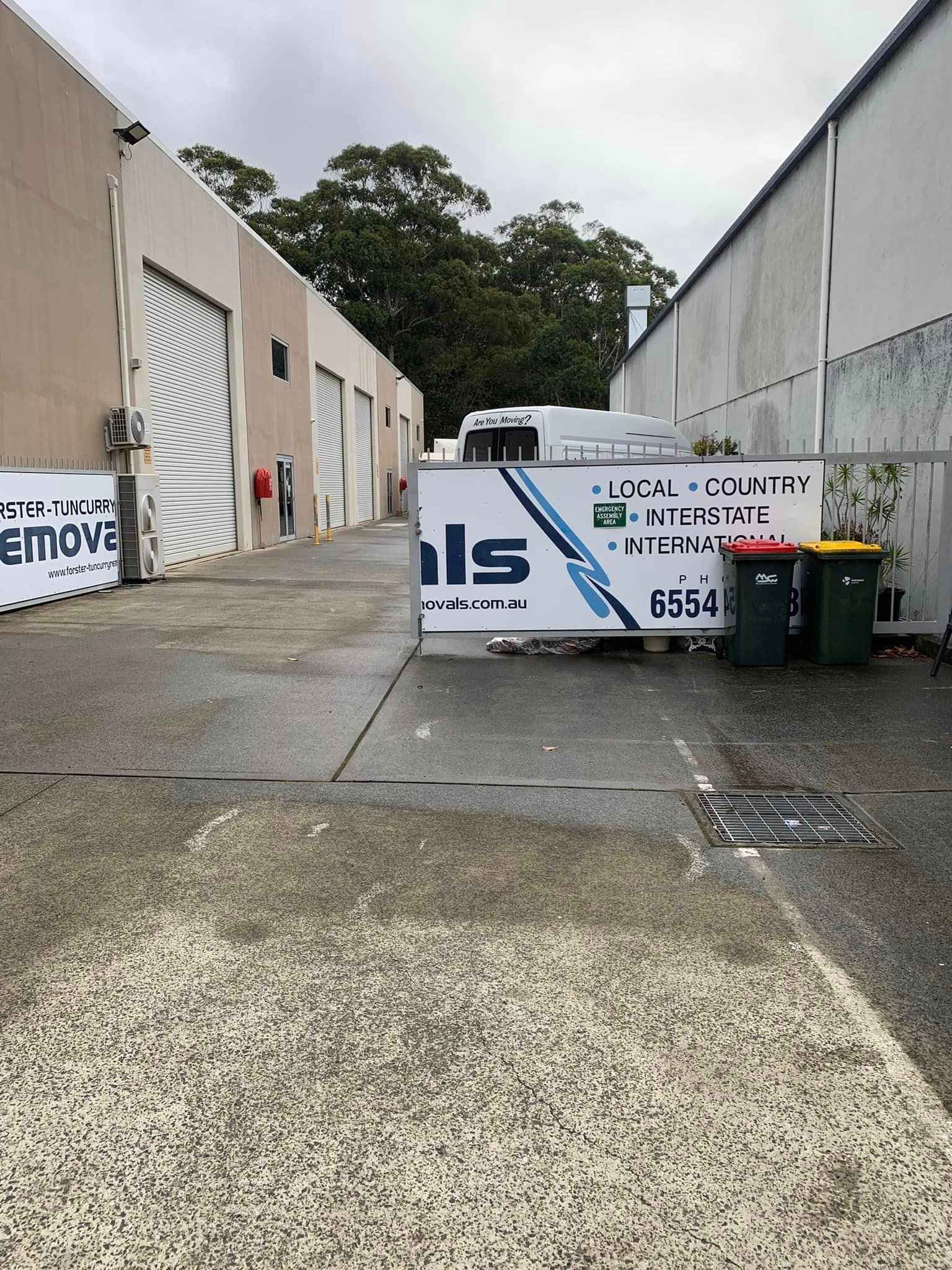 White Sign in the Middle of a Parking Lot Next to a Building — Forster Tuncurry Removals & Storage in Tuncurry, NSW