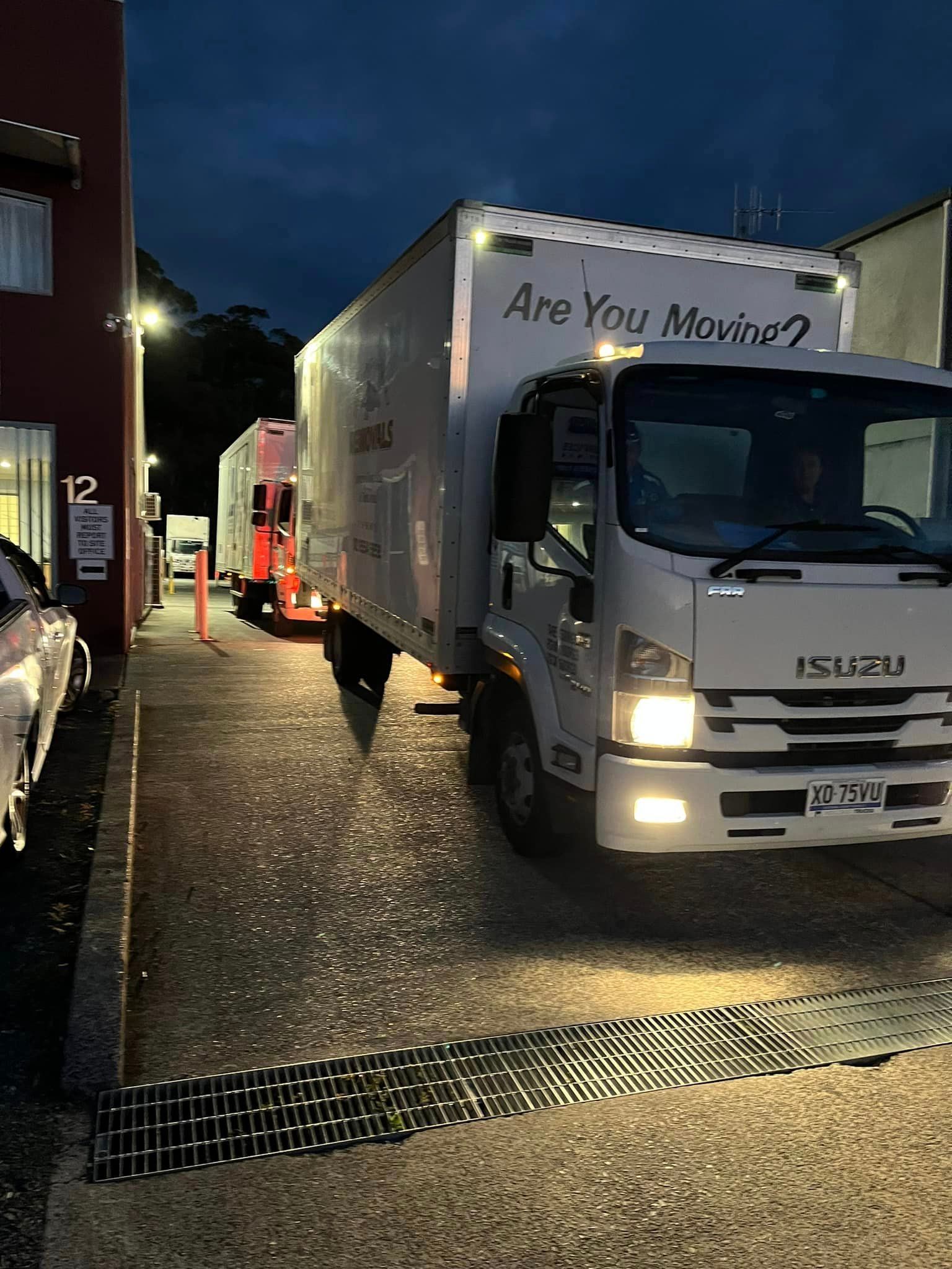 A Row of Moving Trucks Are Parked in a Parking Lot at Night — Forster Tuncurry Removals & Storage in Tuncurry, NSW