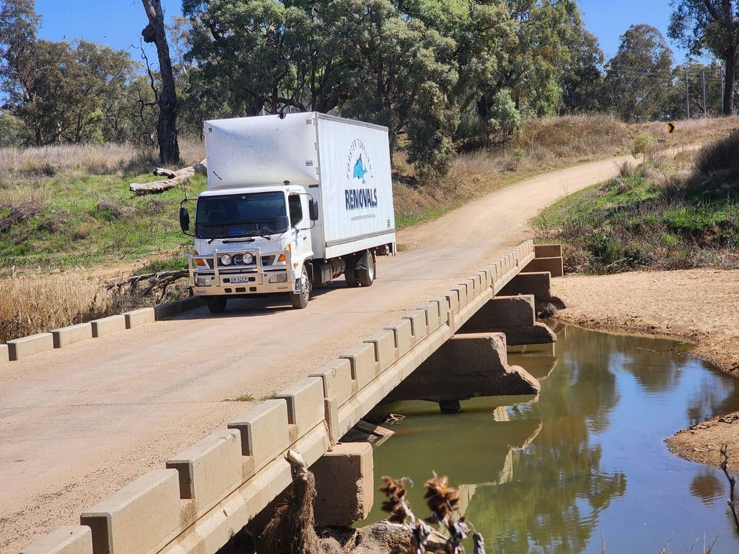 A White Truck Is Driving On A Bridge Over A Body Of Water — Forster Tuncurry Removals & Storage In Forster, NSW