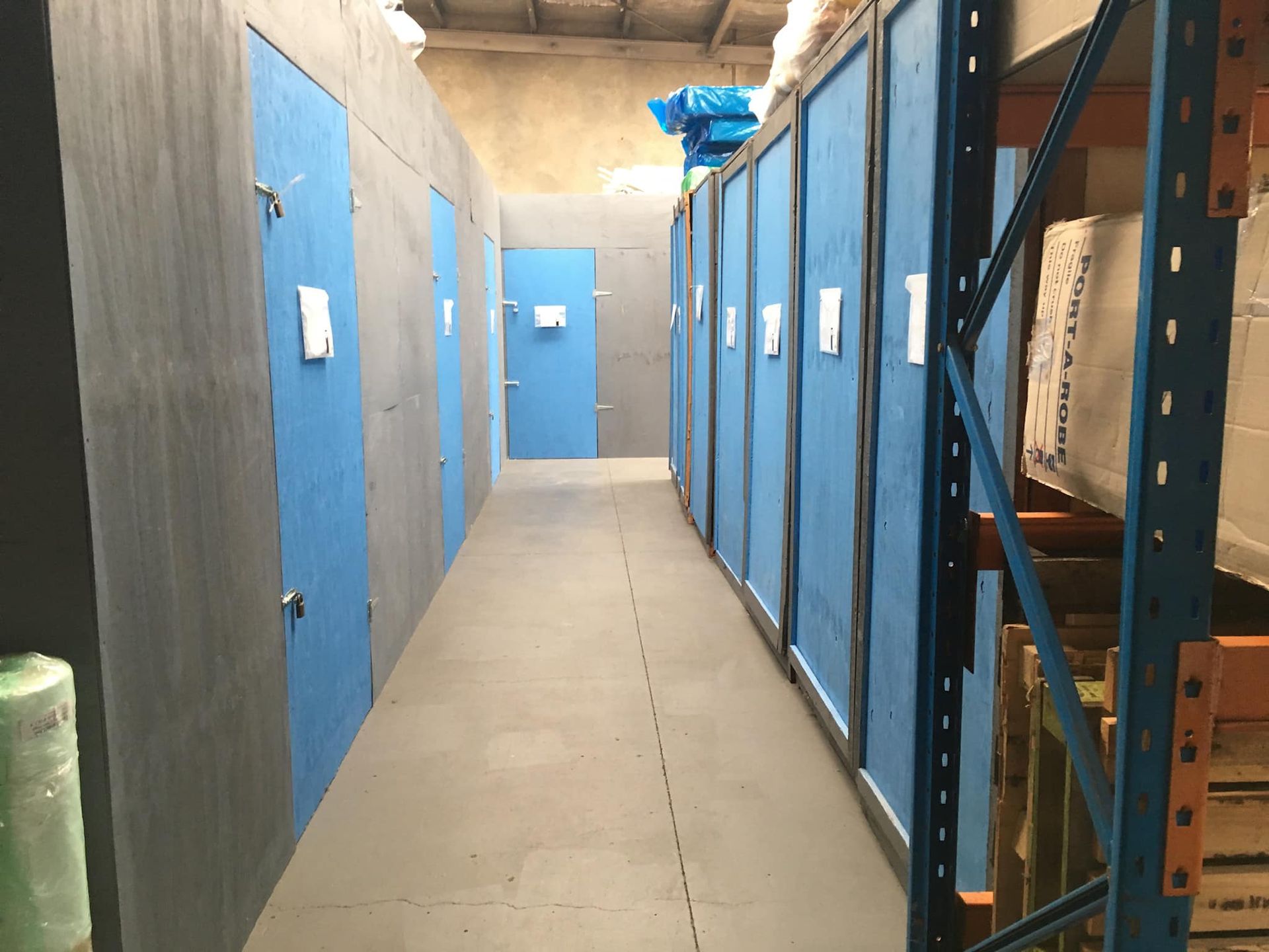 Storage Units With Blue Doors Line a Narrow Concrete Hallway — Forster Tuncurry Removals & Storage in Tuncurry, NSW