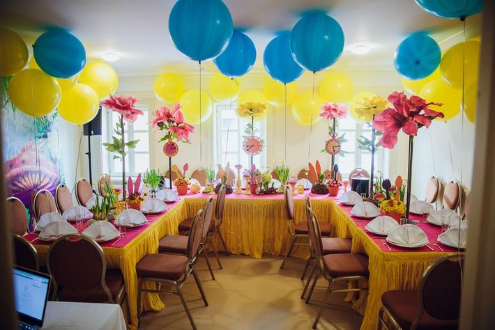 A room filled with tables and chairs decorated with balloons and flowers.