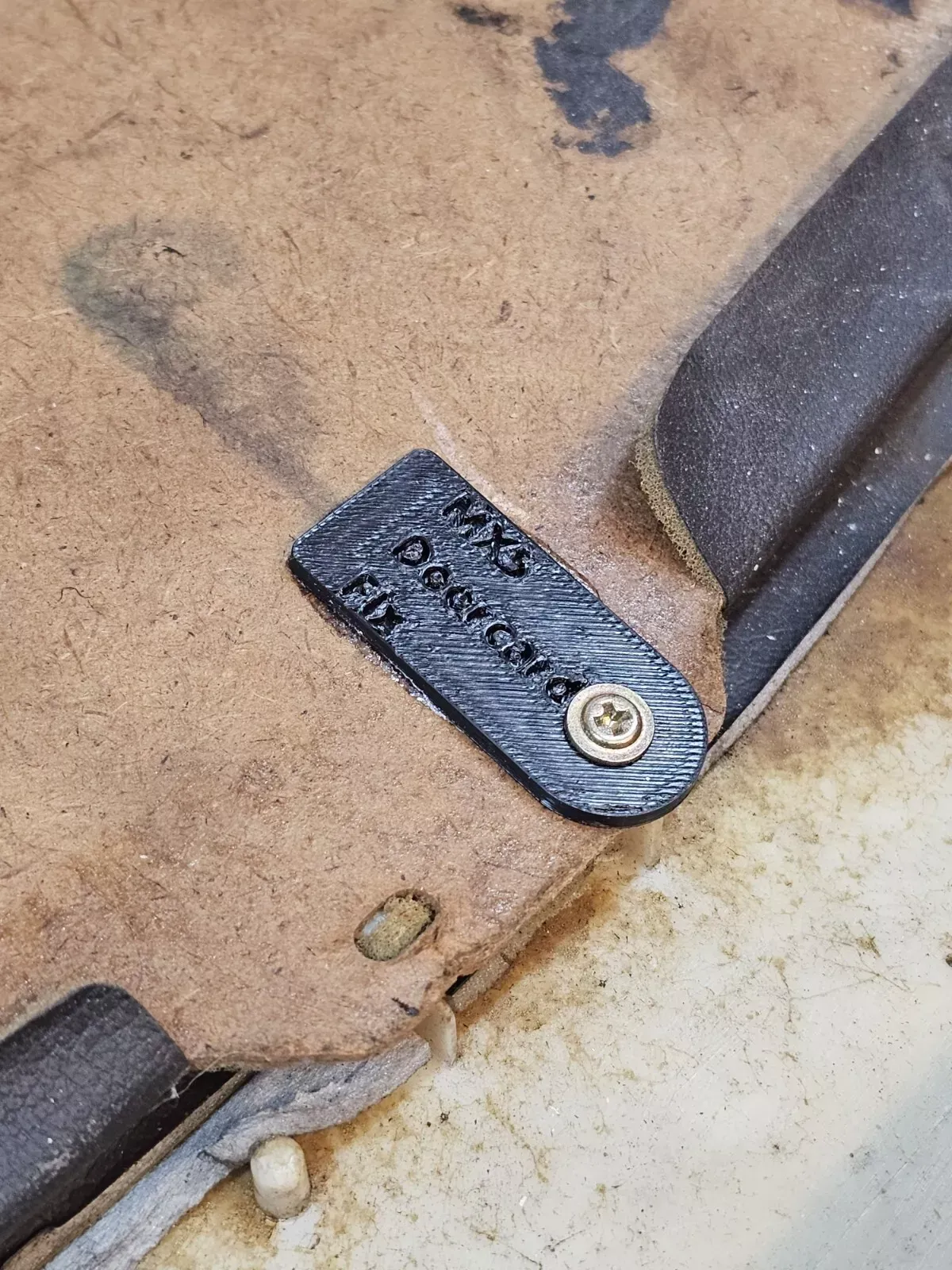 Close-up view of a tag, attached by a screw, reading