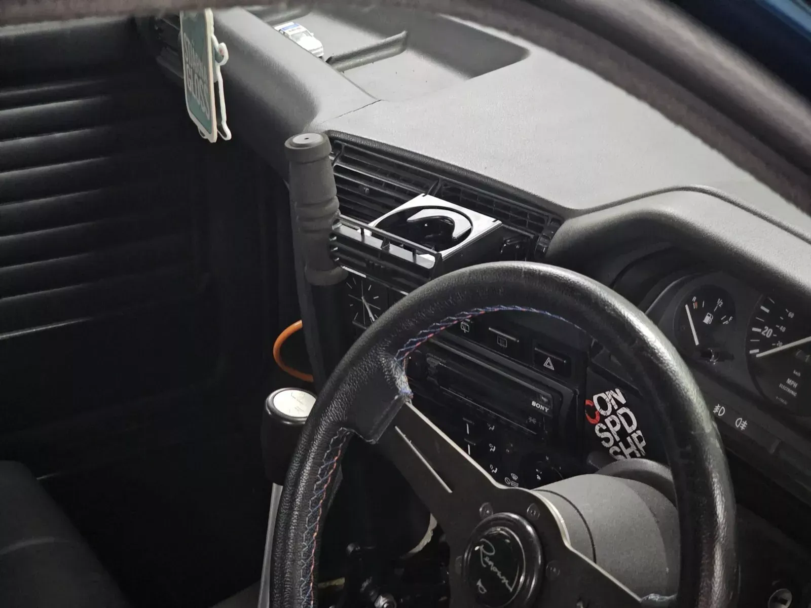 Black interior of a car with a steering wheel, dashboard, gear shift, and gauges.