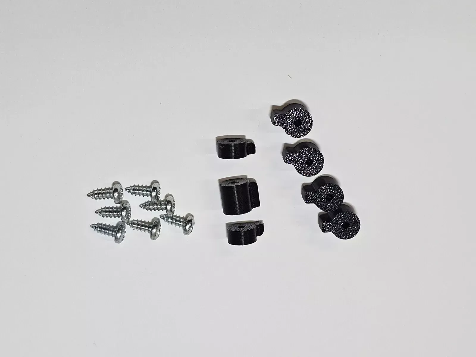 Nine screws, three black plastic clips, and three textured black clips on a white background.