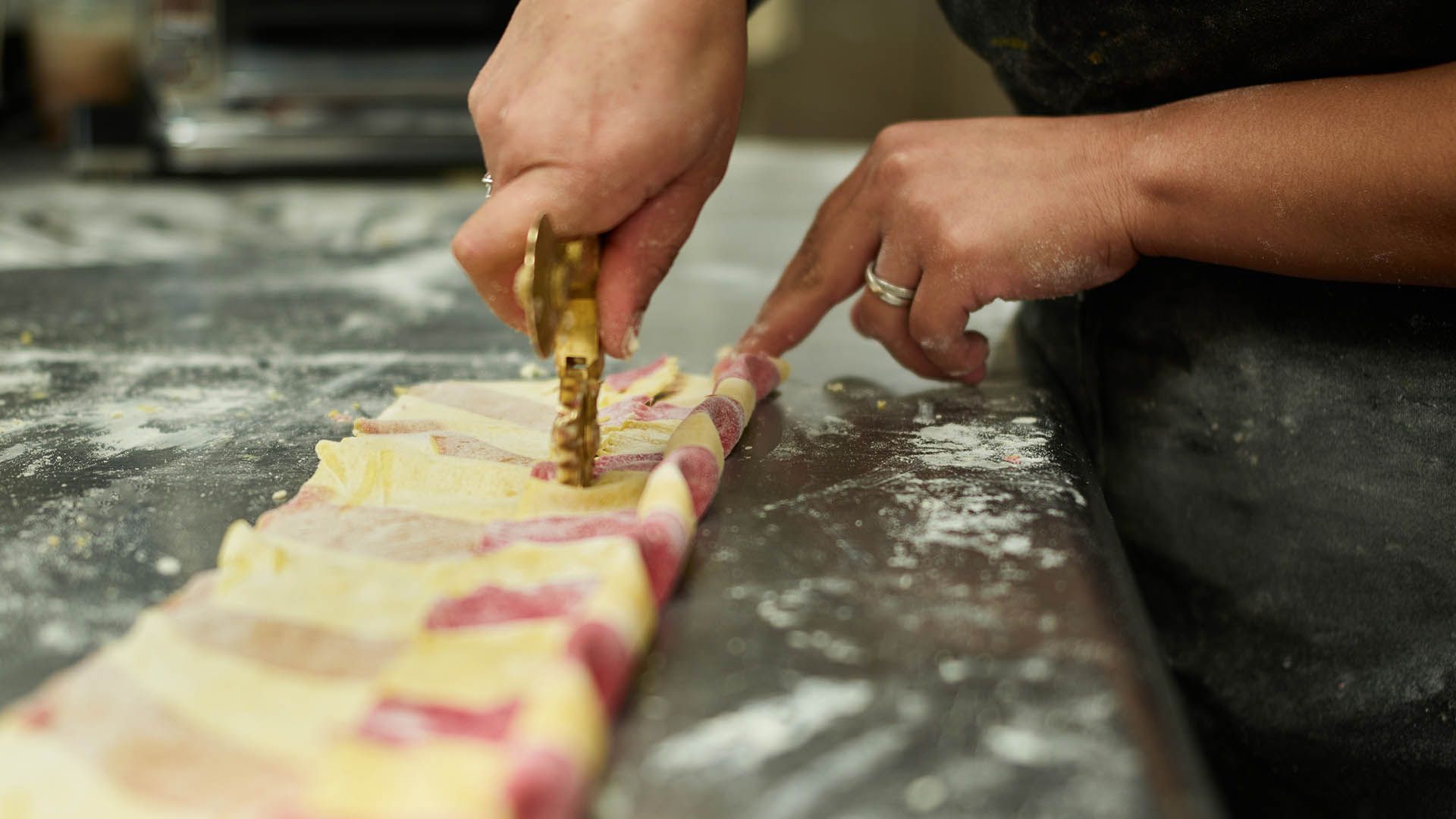 A person is cutting dough with a cutter on a table.