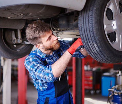 Auto Diagnostic Service — Mechanic Checking the Wheel in Hayden, ID