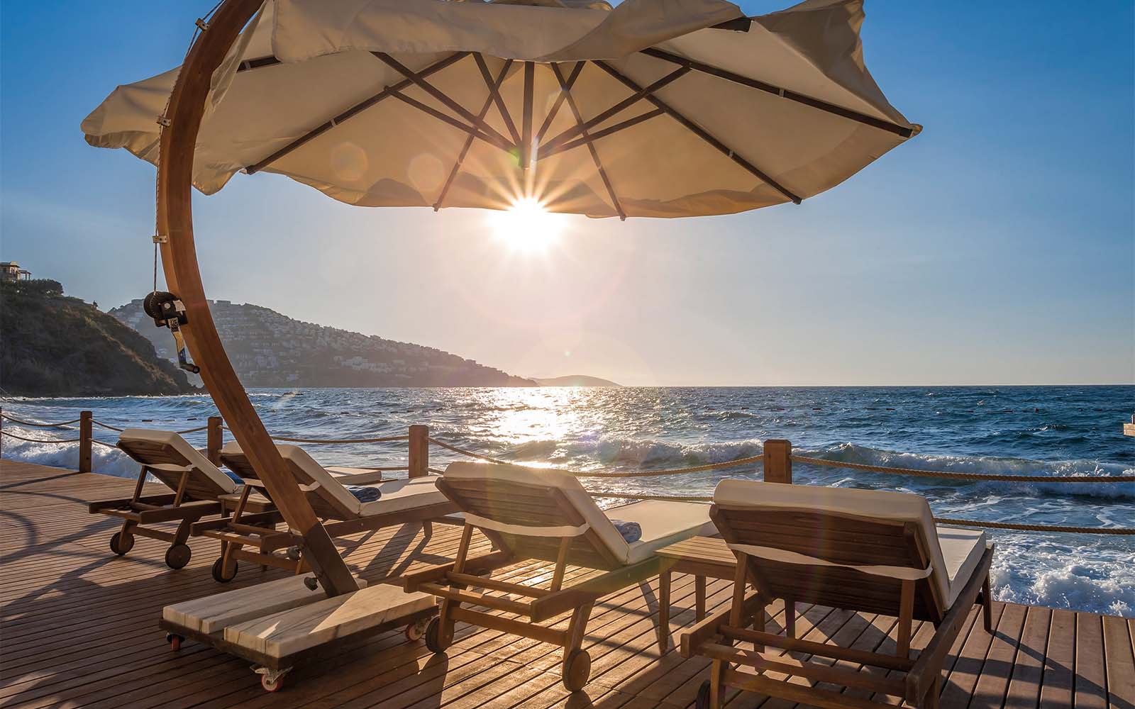 The sun is shining through the umbrella on the beach.
