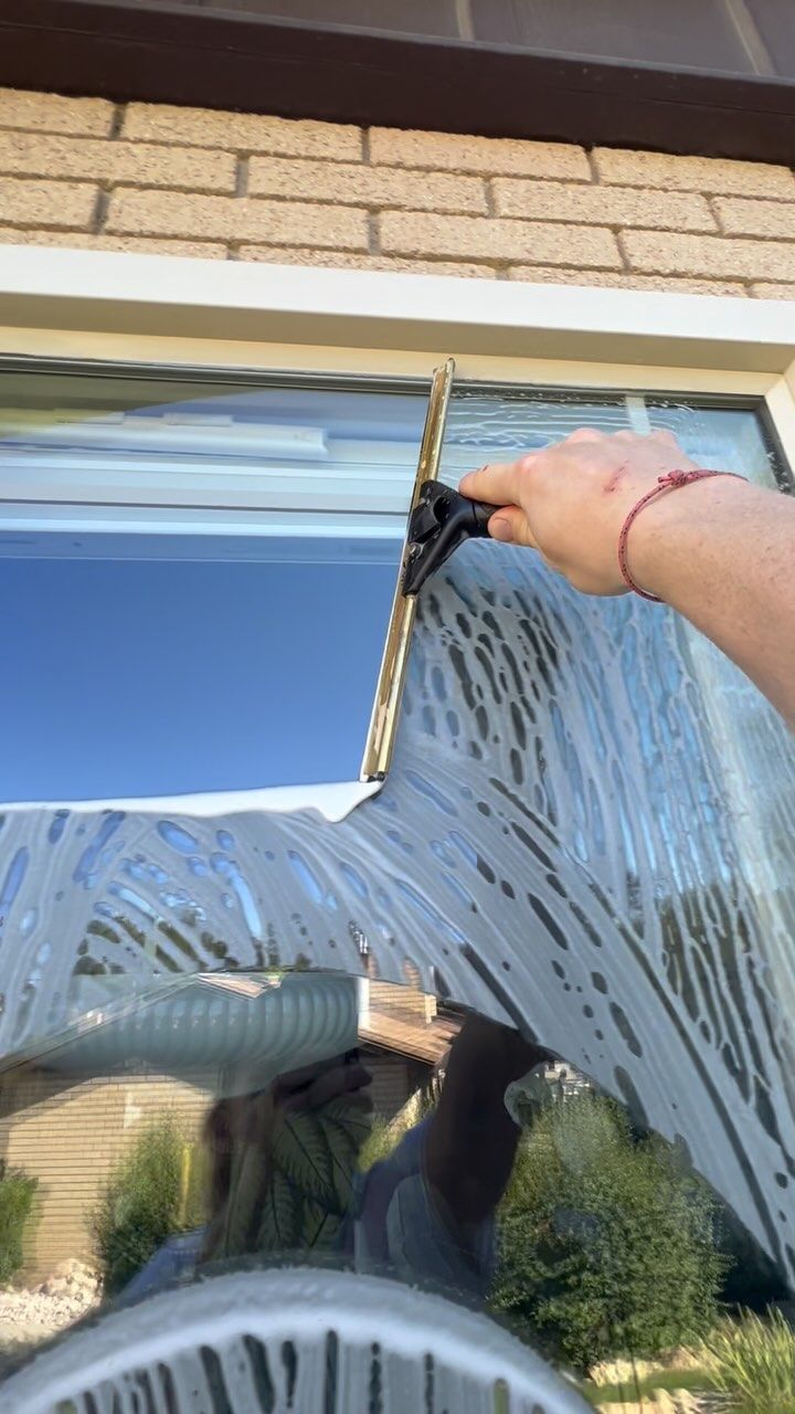 A person is cleaning a window with a squeegee.