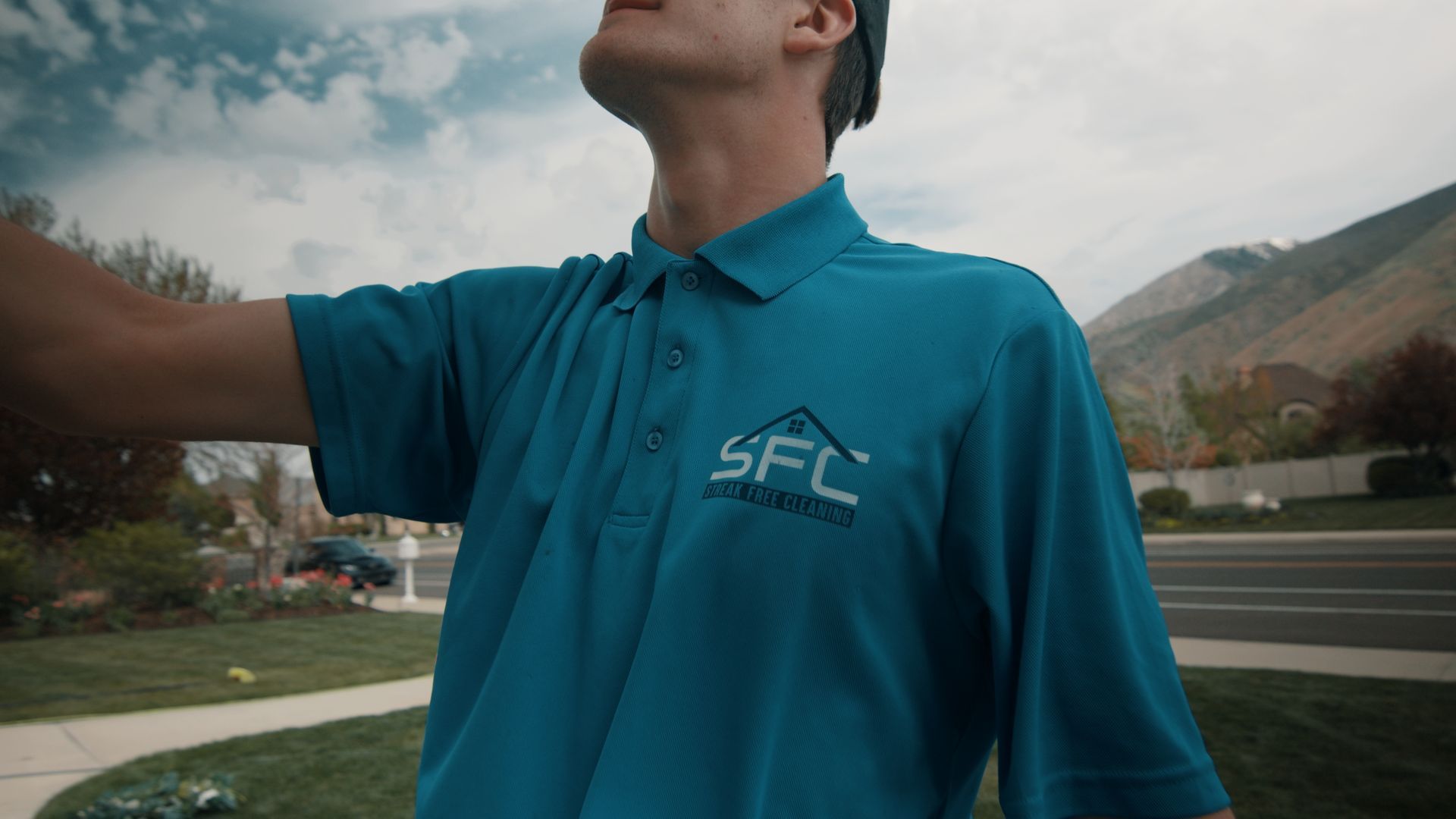 A man in a blue polo shirt is standing in front of a mountain.