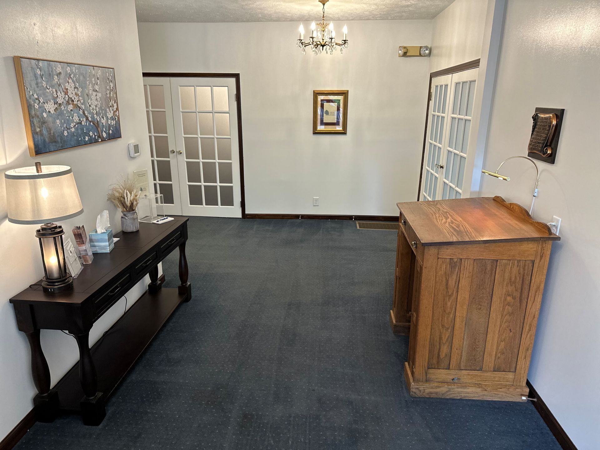 A living room with a wooden table and a wooden desk.
