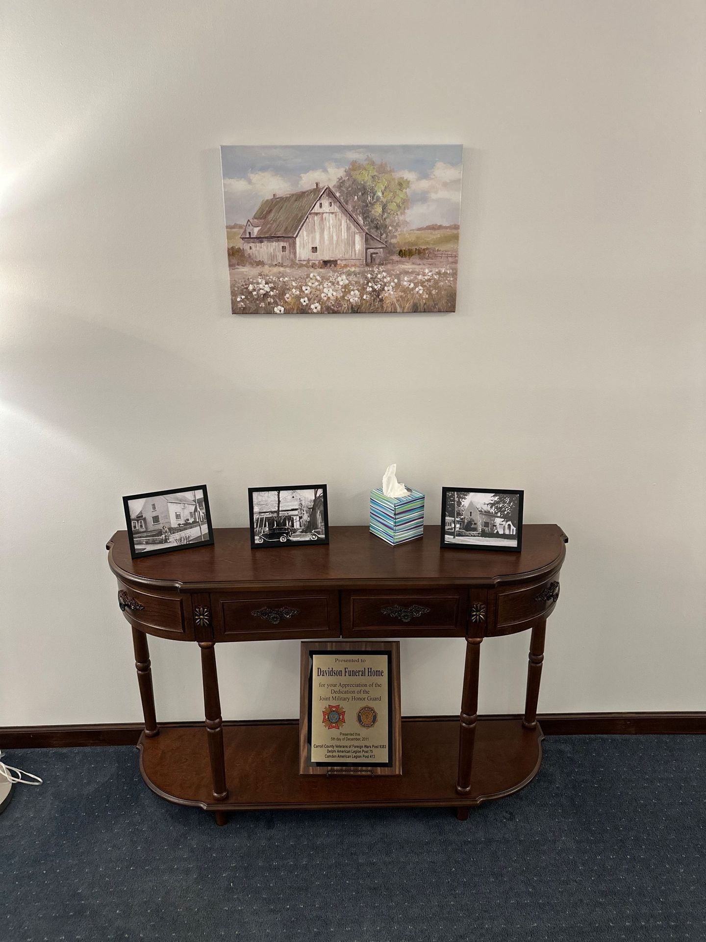 A wooden table with pictures on it and a painting on the wall above it.