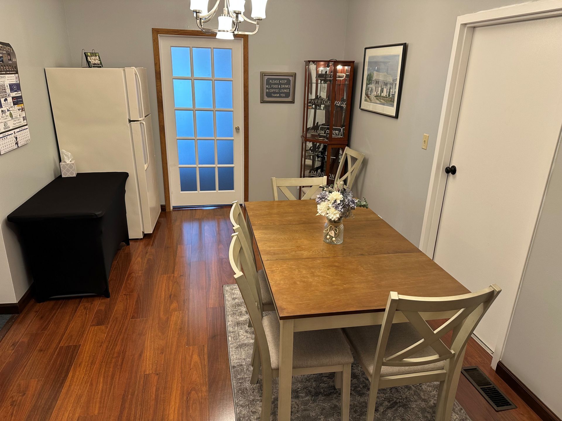 A dining room with a table and chairs and a refrigerator.