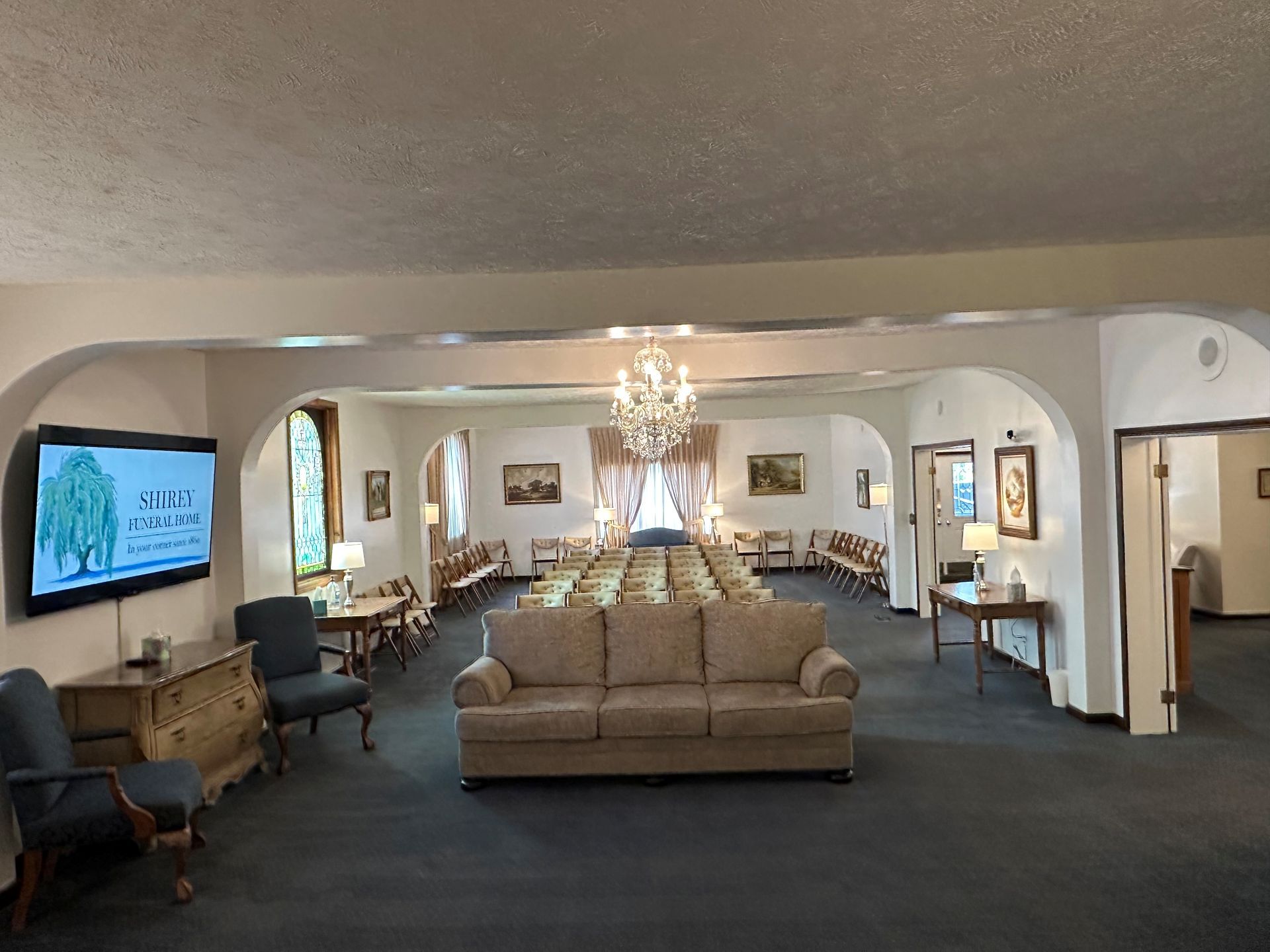 A large room with a couch , chairs , and a television.