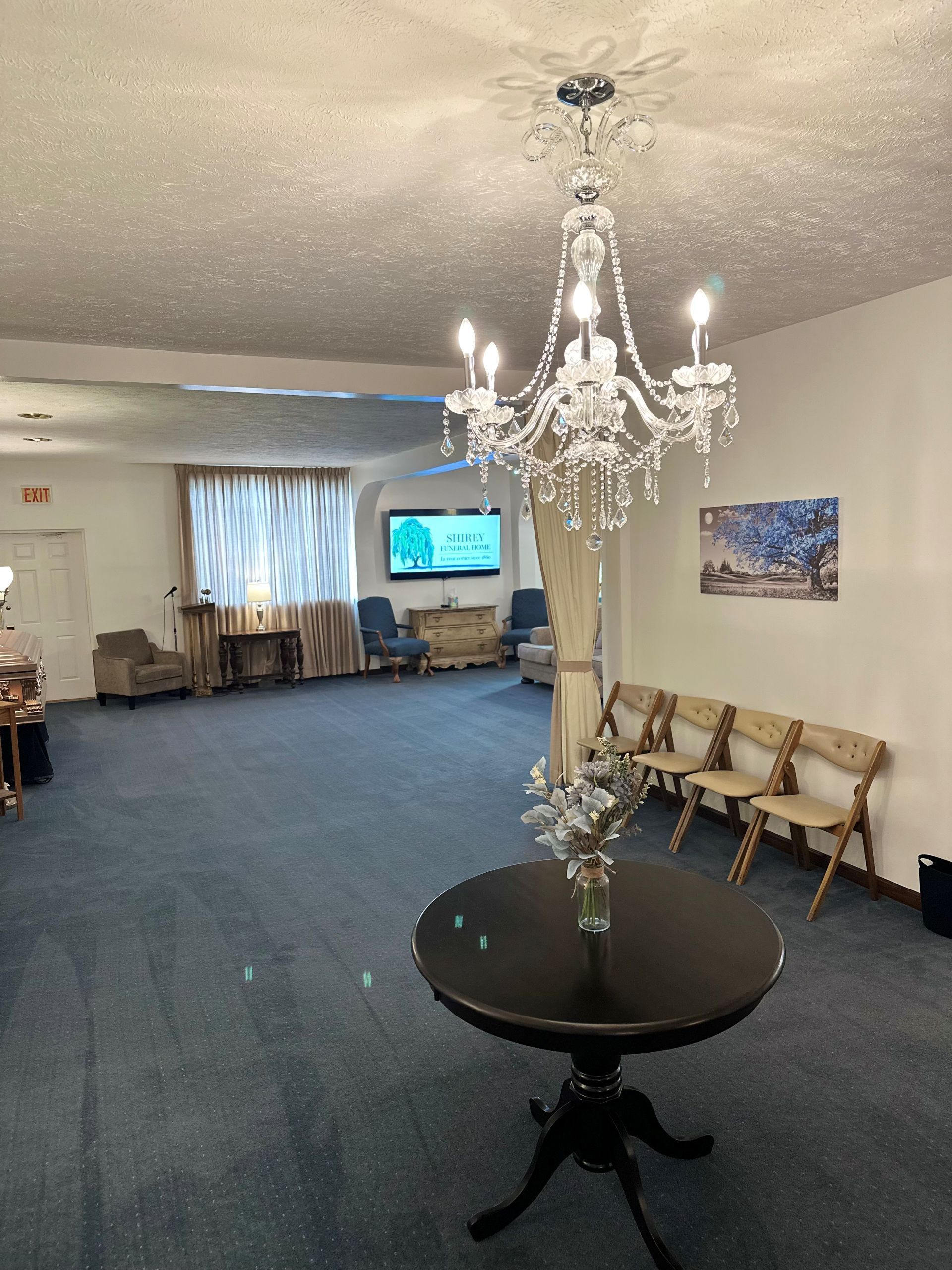 A room with a table and chairs and a chandelier hanging from the ceiling