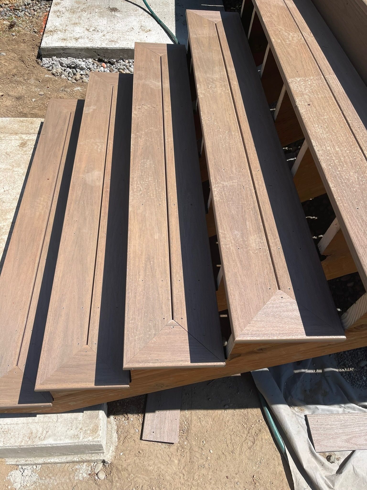 A set of wooden stairs under construction, featuring light brown planks with vertical gaps and dark shadows in between.