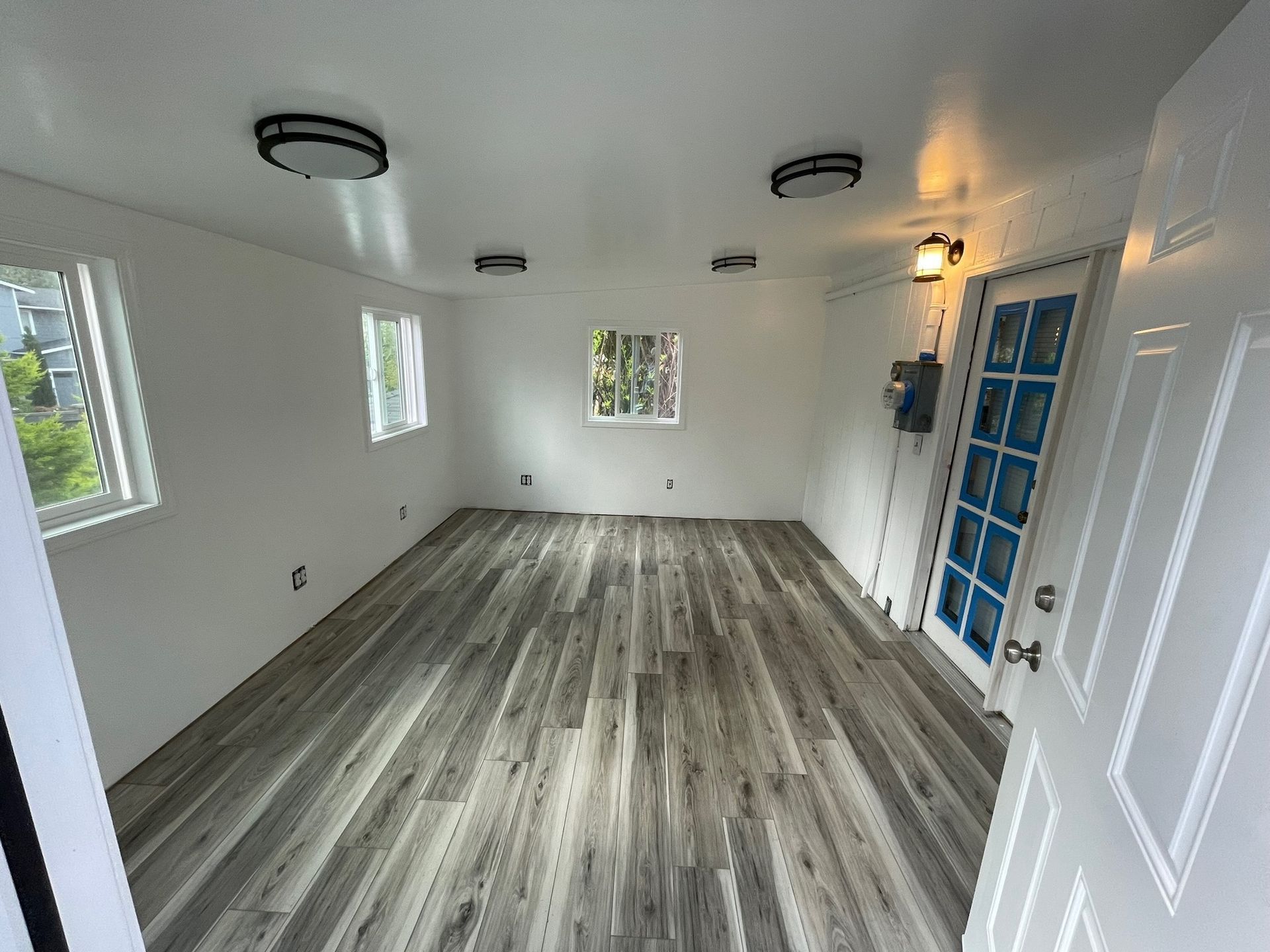 Kitchen island with white marble countertop and cooktop, stainless steel range hood, and dark green cabinetry.