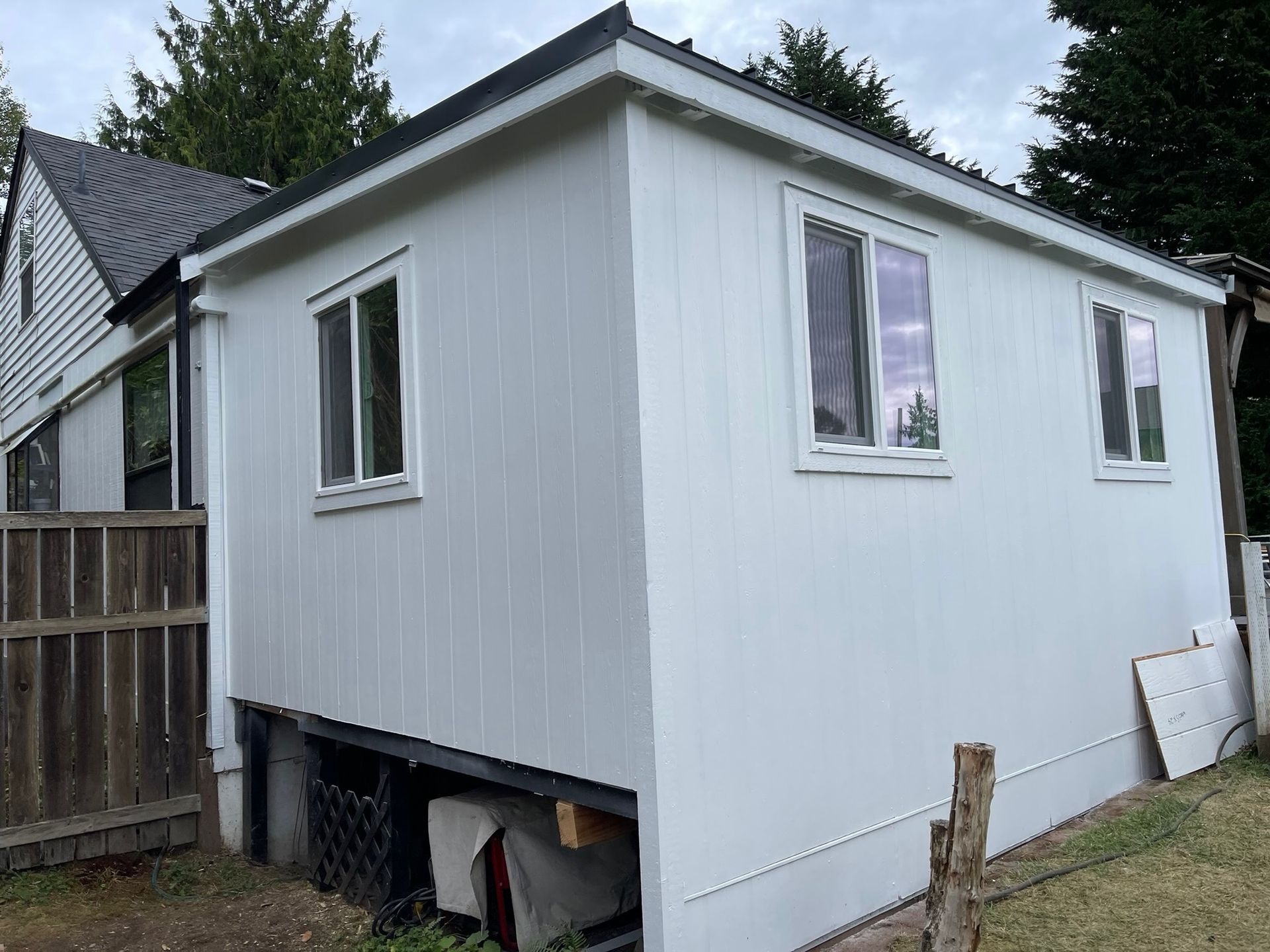 A single-story house with dark blue horizontal siding, a white front door, and a stone patio area.