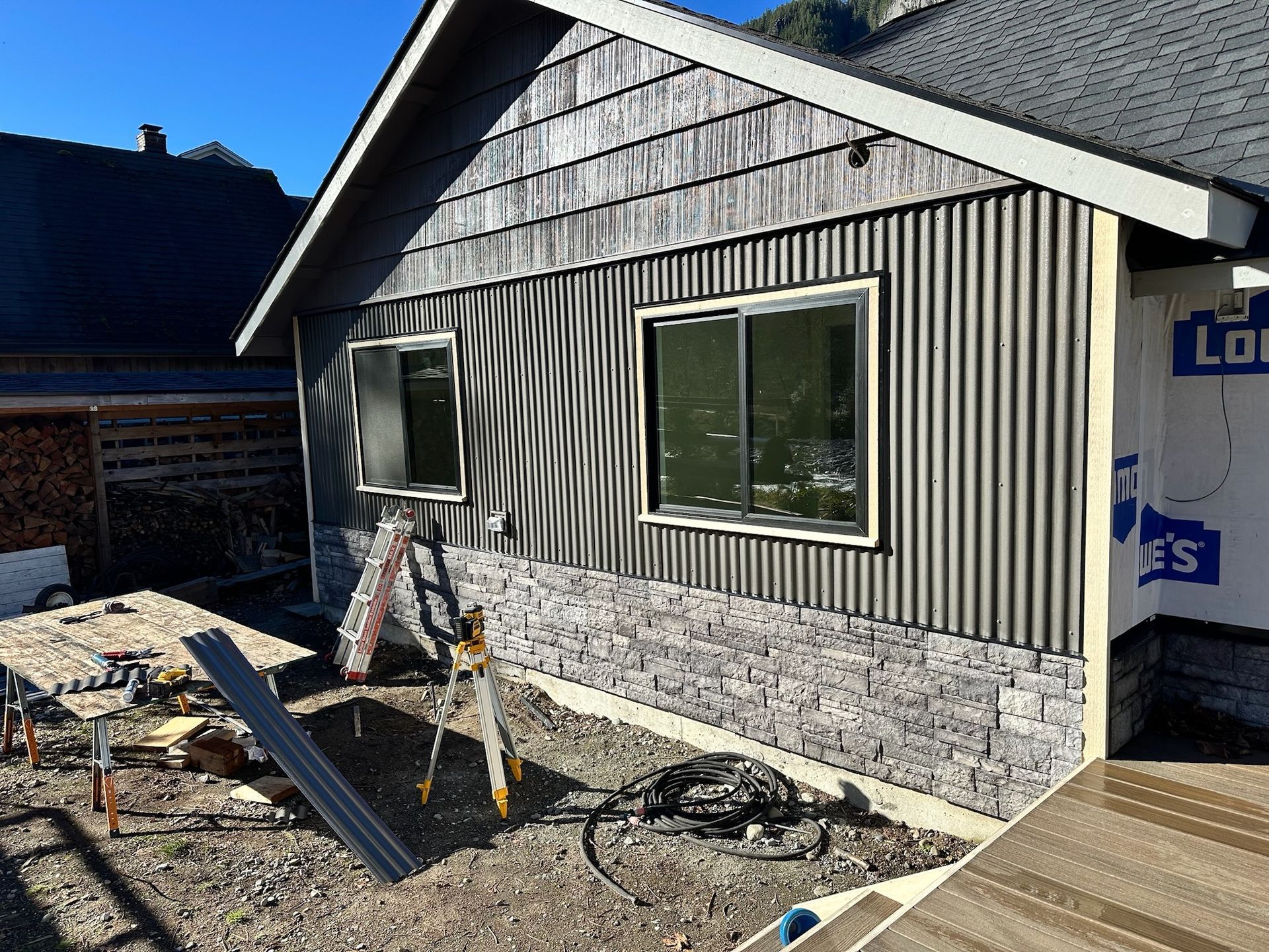 A new gray composite deck attached to the rear of a blue-sided house with white trim.