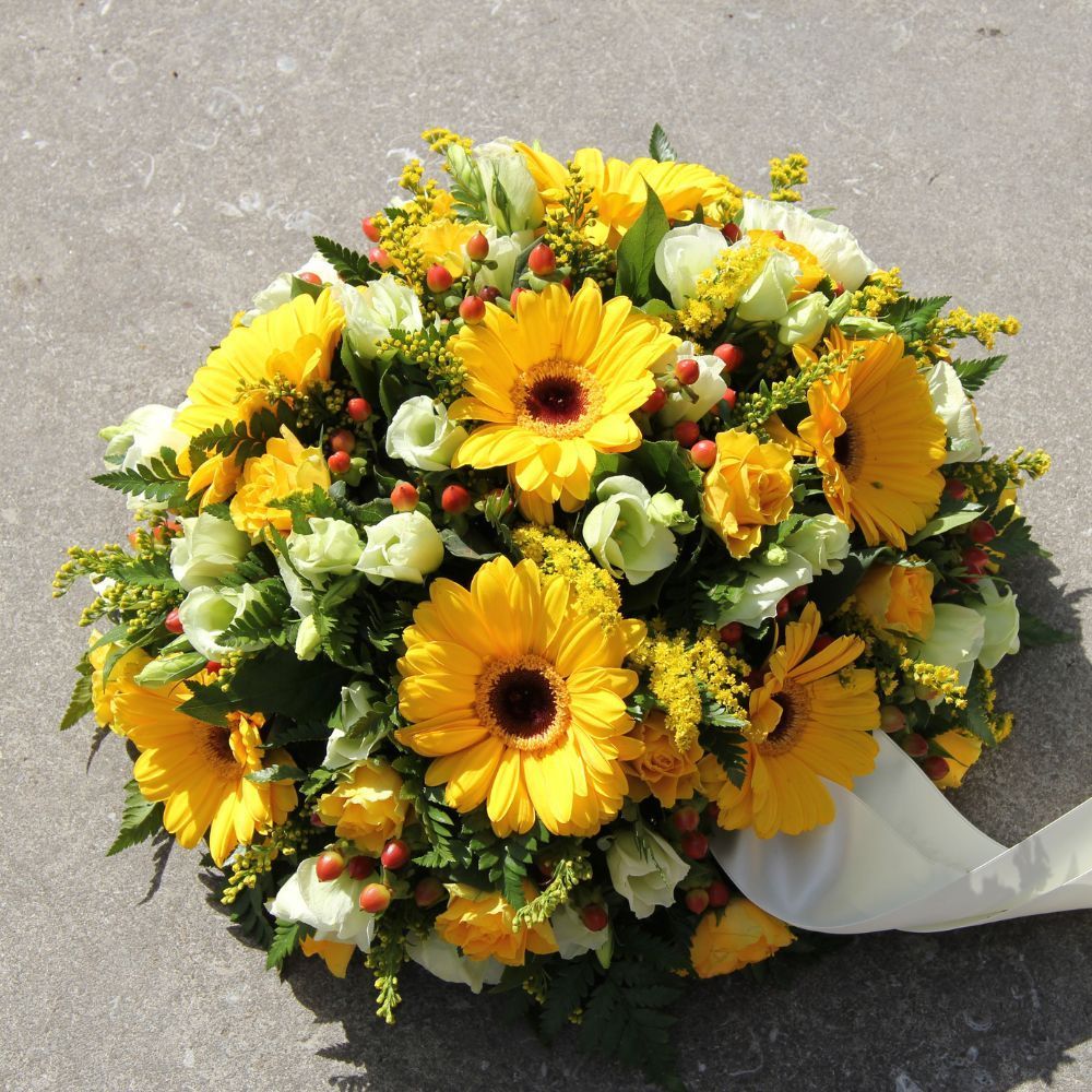 A bouquet of yellow and white flowers with a white ribbon