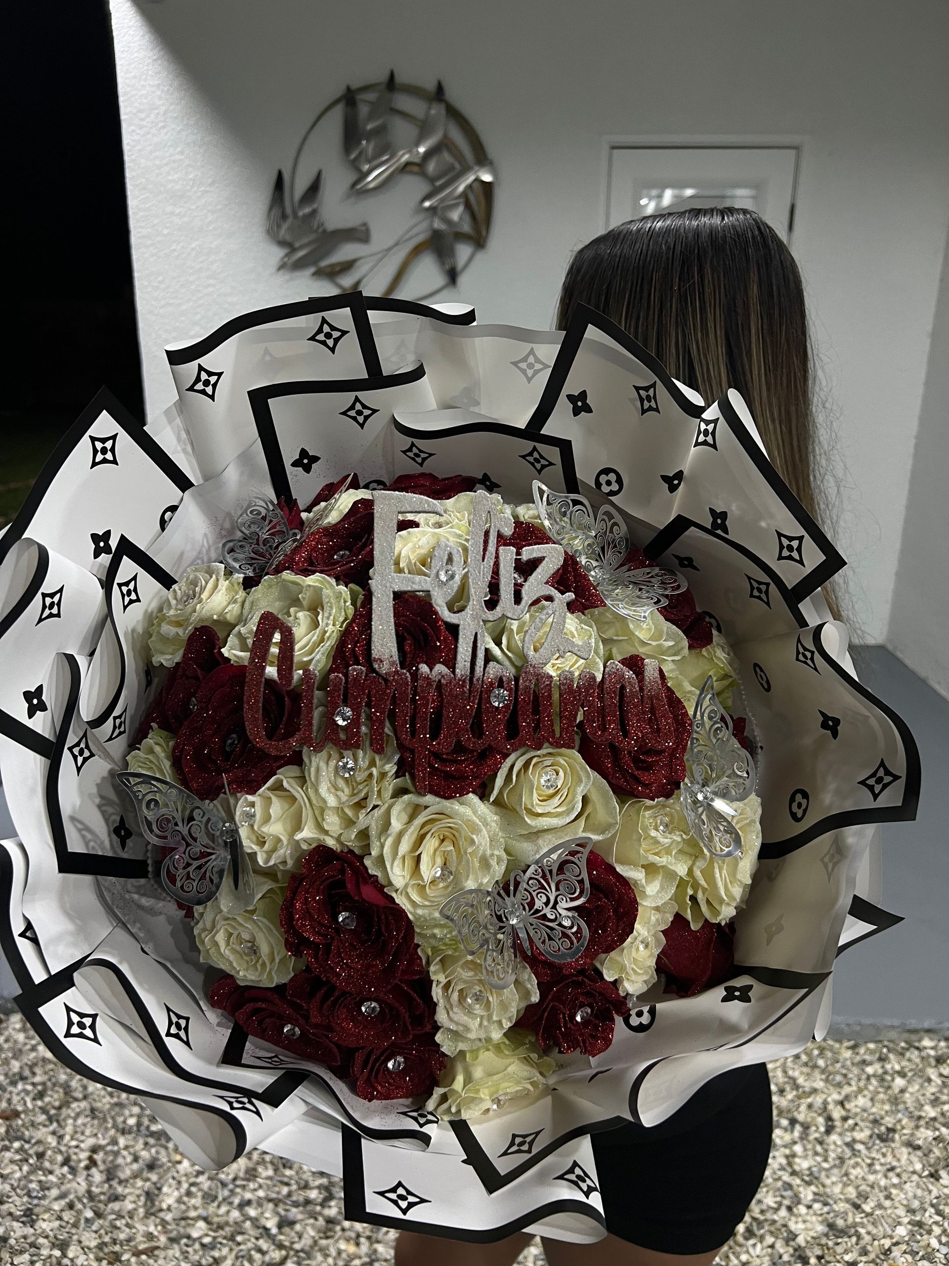 A woman is holding a large bouquet of flowers with the word feliz on it.