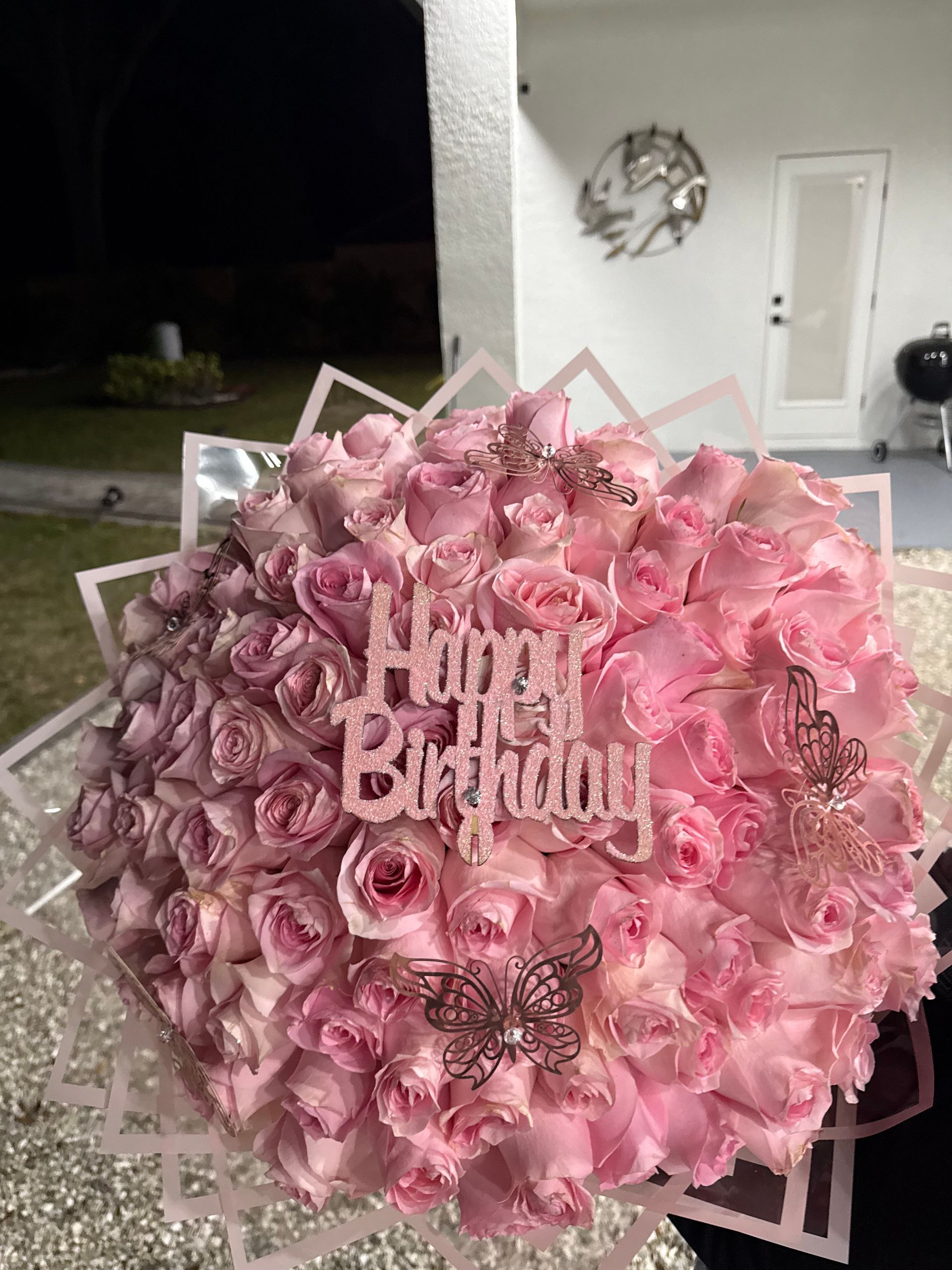 A bouquet of pink roses with a happy birthday sign on top.
