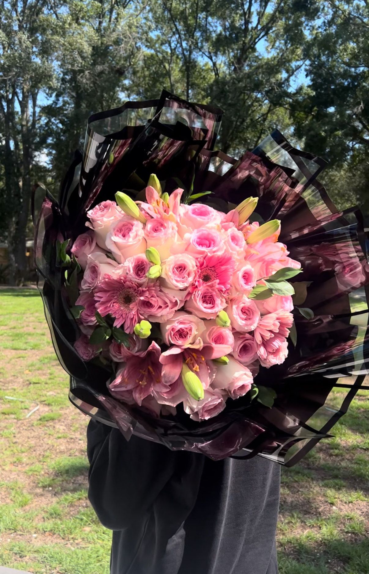 A person is holding a large bouquet of pink flowers.