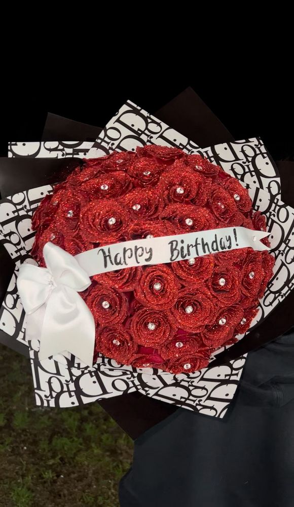 A bouquet of red roses with a white ribbon that says happy birthday
